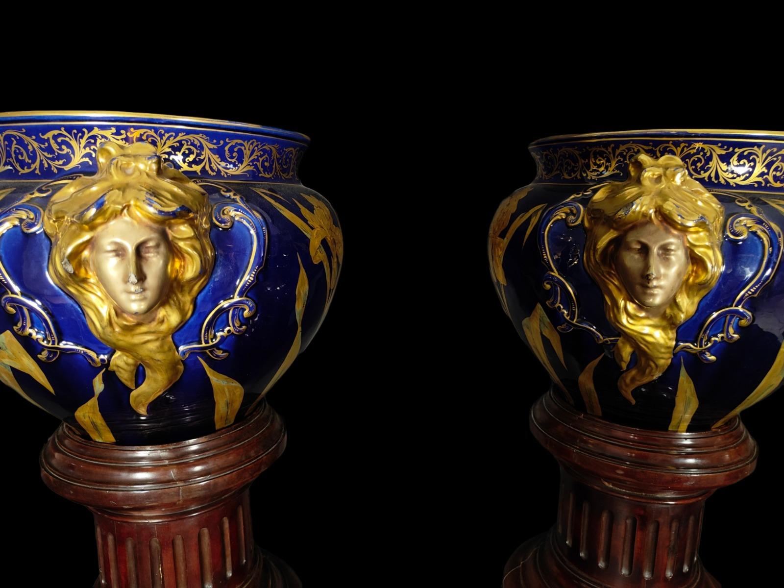 Pair of art nouveau planters. Cobalt blue enamel and partially gilt. With illegible marks on the base. On column-shaped wooden bases varnished simulating mahogany.With some minore looses and repair-please see photos. Measurements: 31 x 52 x 40 cm;