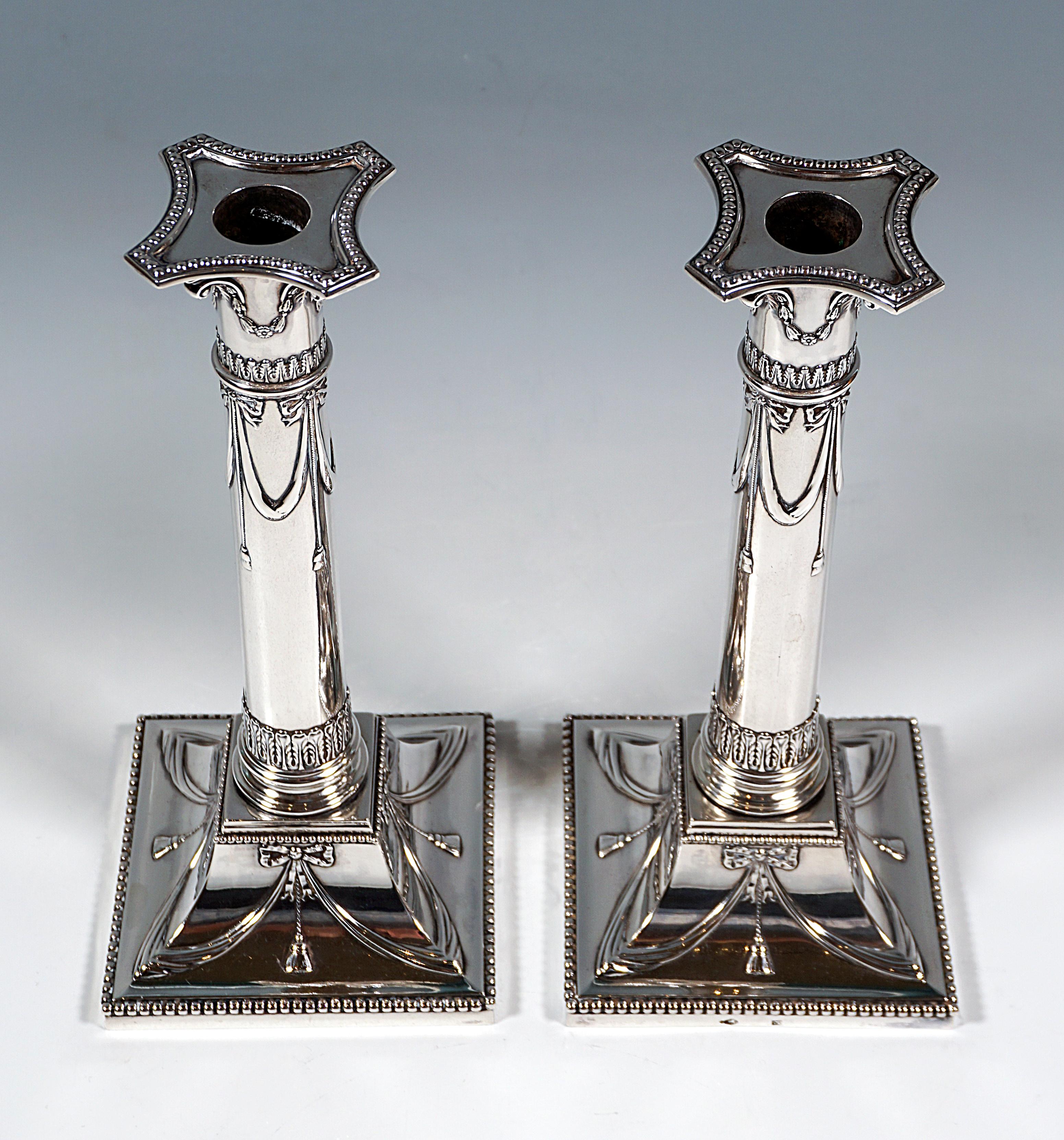 Two elegant silver candle holders on a square plan, base plate surrounded by a bead stick, base raised in a groove and forming a small square pedestal, grooved walls decorated with bow and ribbon reliefs, ending with a bead stick, round, smooth