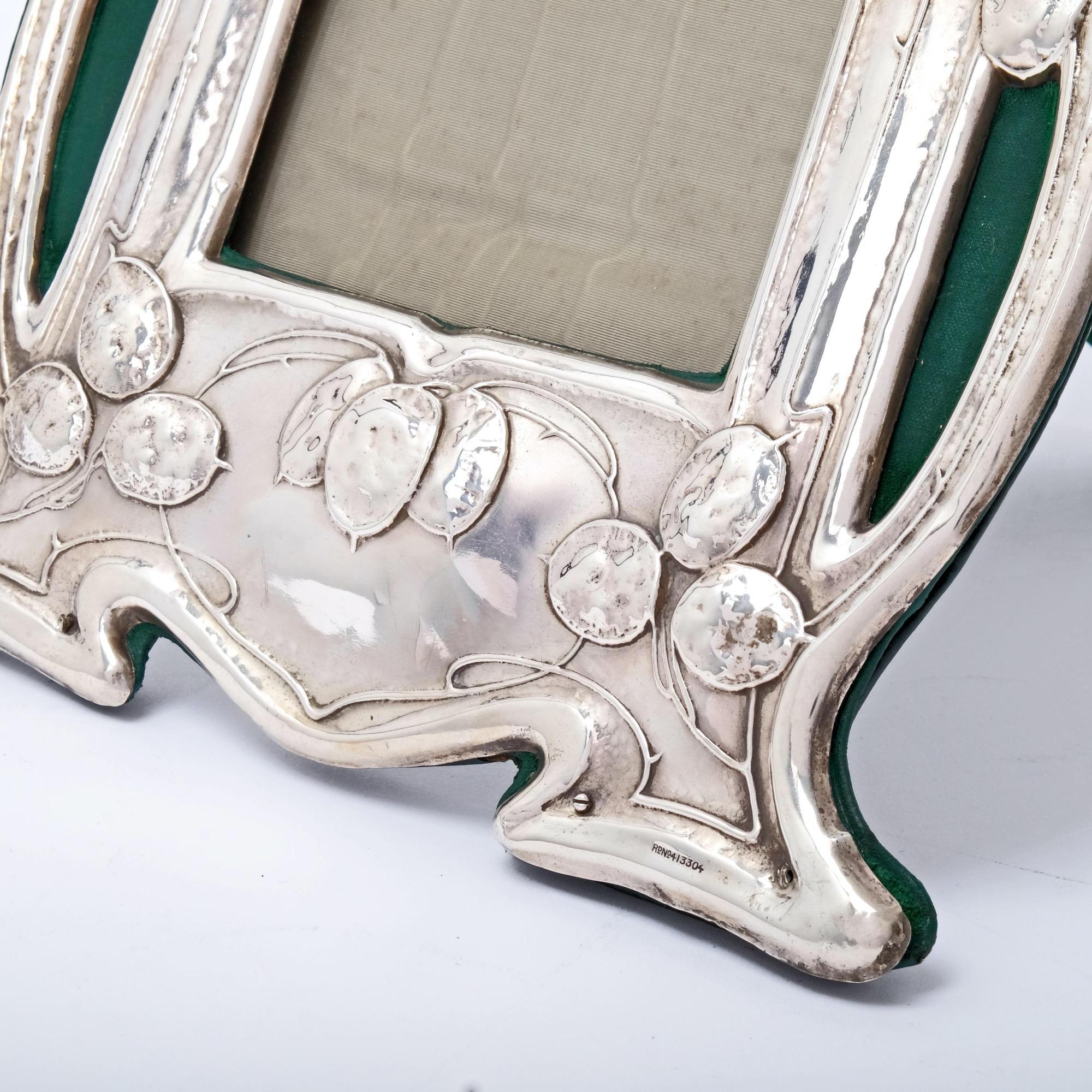 An exceptionally attractive pair of antique Edwardian Art Nouveau photo frames. The shaped and openwork frames are embossed with naturalistic leaves and tendrils that are so reminiscent of the Art Nouveau style. Fitted with green leather backs and