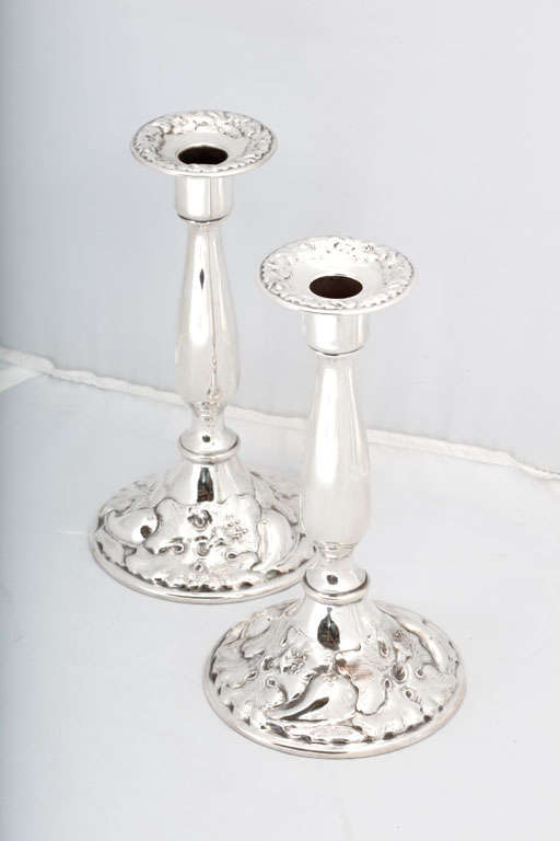 Beautiful pair of Art Nouveau, sterling silver candlesticks, The Adelphi Silver Co., New York, circa 1895-1905. Bases are covered with lovely Art Nouveau flowers; floral motif is picked up in the removable bobeches. Each candlestick measures 8 3/4