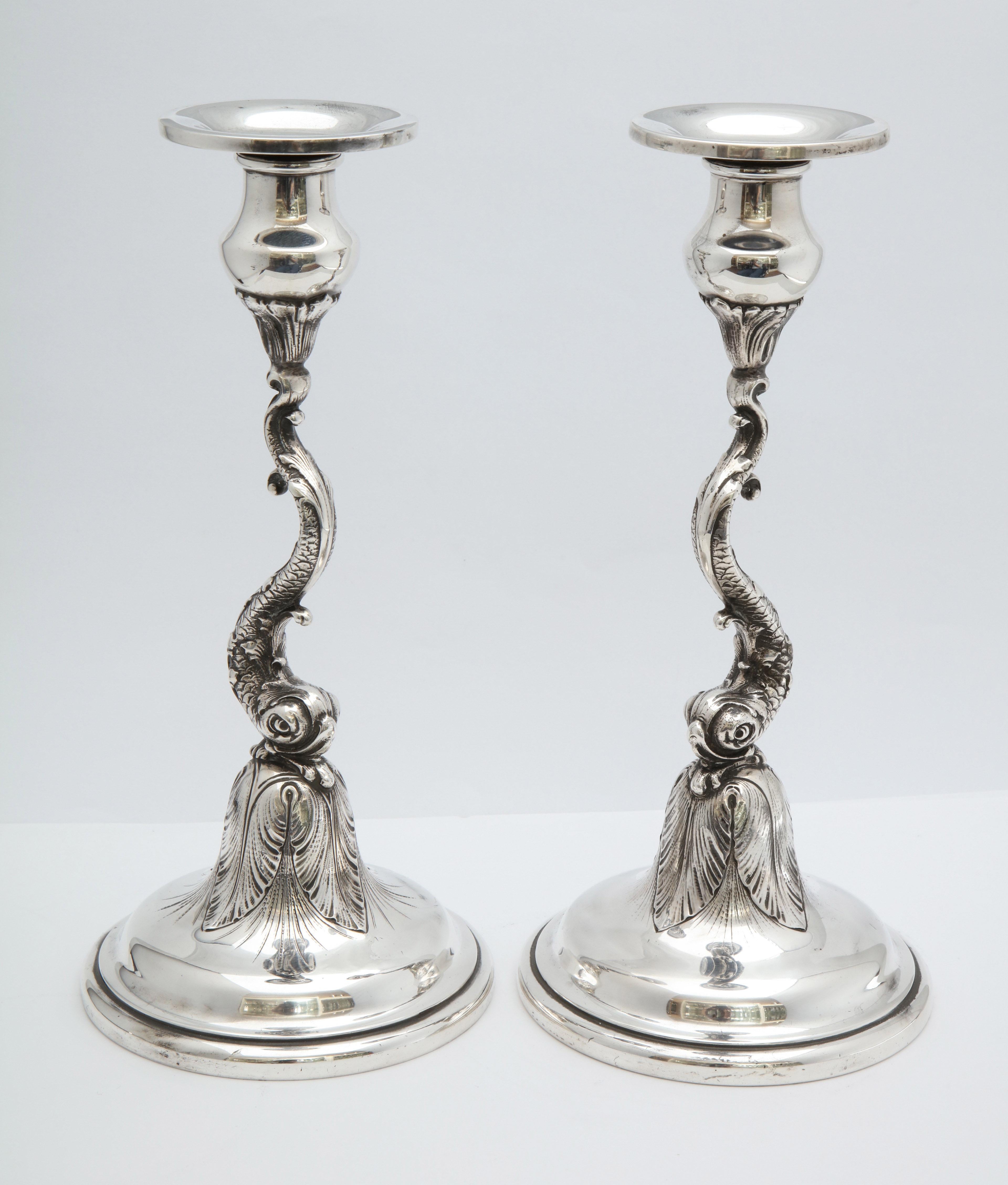 Pair of sterling silver, Art Nouveau, Dolphin-form candlesticks, made for The Spaulding Co., Chicago (by the Redlich Silver Co.) circa 1900. The stem of each candlestick is the full head and body of a dolphin. Weighted. Each candlestick measures 10