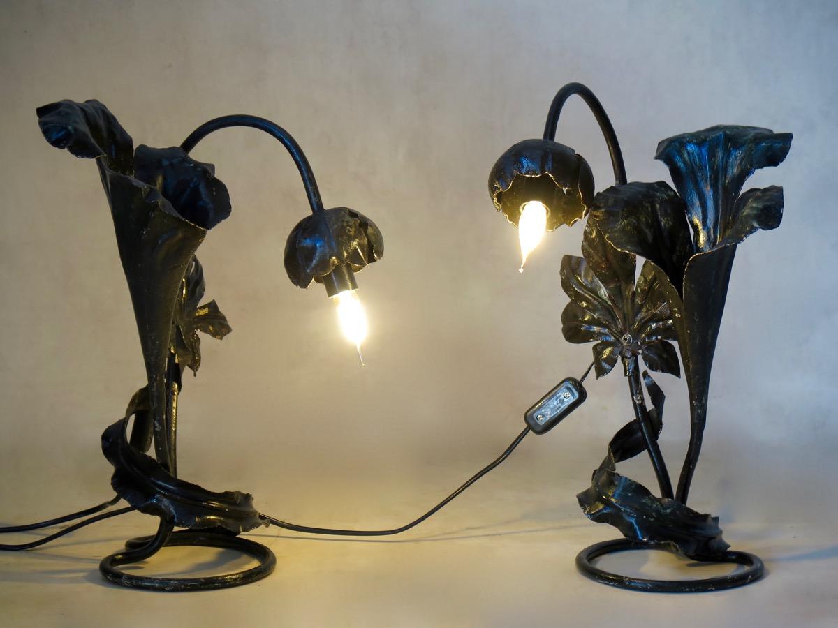Elegant pair of Art Nouveau style lamps, the light in a large flowerhead. They rest on coiled bases and are decorated with large palm-like leaves. Blackened metal.