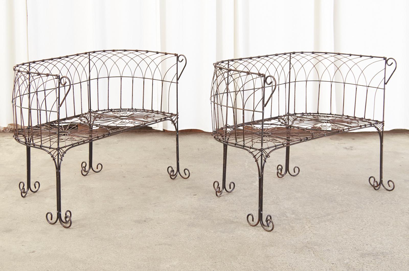 Splendid pair of wrought iron and wire French patio and garden benches made in the Art Nouveau taste. The benches or settees feature an iron frame decorated with gracefully curved wire lattice designs. Supported by straight legs ending with scrolled