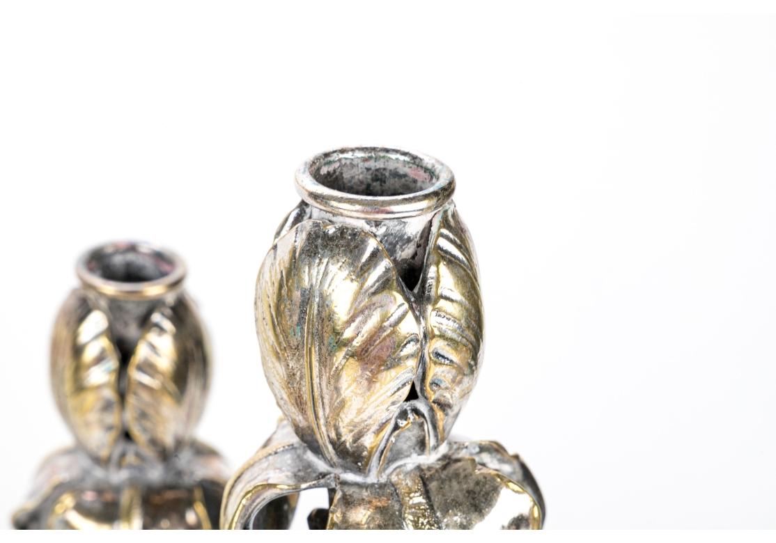 Finely crafted heavy silvered bronze candelabra with traces of vermeil overall. With four leafy scrolled arms for the candle sockets in the form of iris flowers, each with unfurled realistic petals. Mounted on elegant swirled leafy stems and bases. 