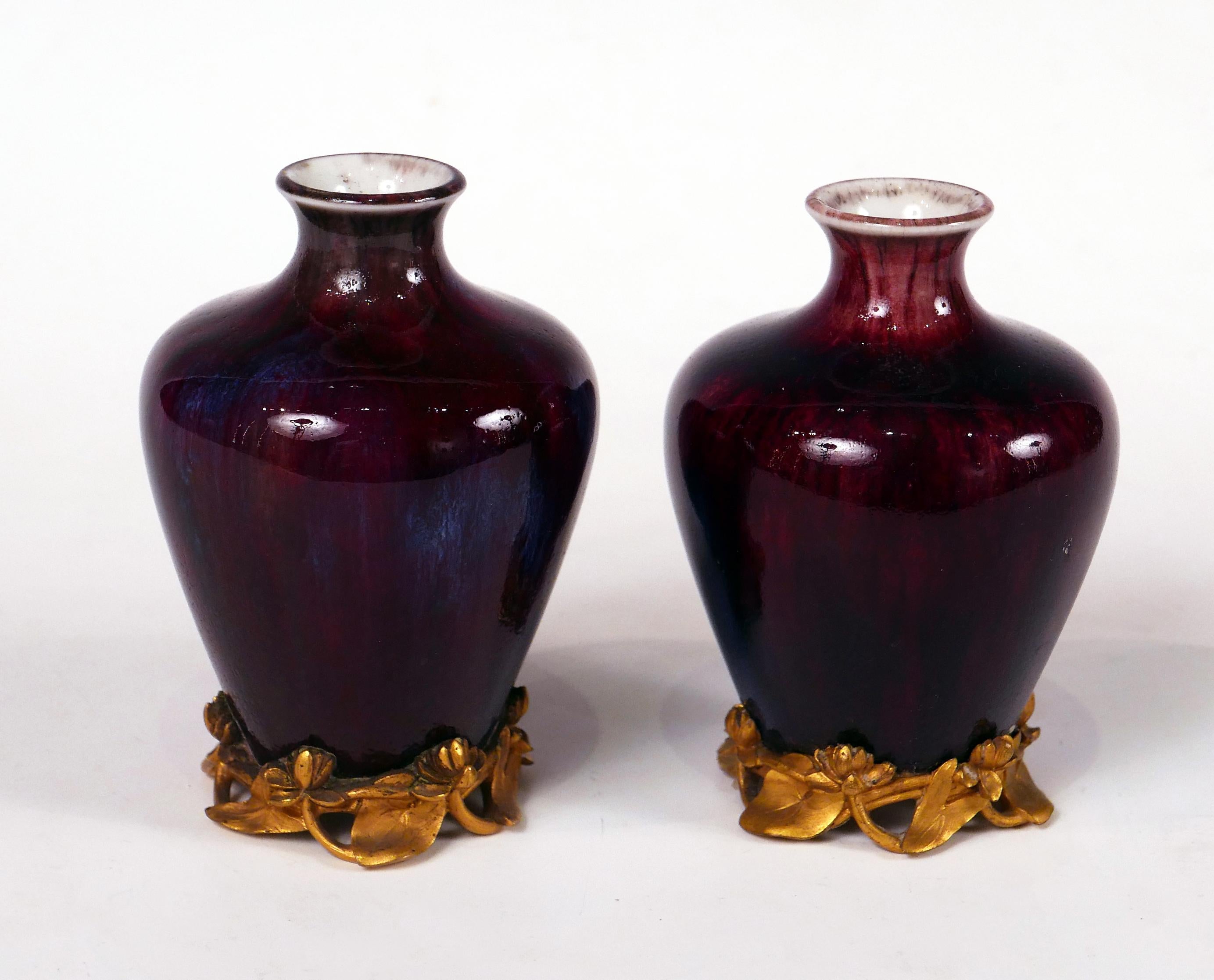 Signed and dated 1902.

Charming pair Art Nouveau vases in flamed and enameled “sang-de-boeuf” porcelain, resting on a gilded bronze base decorated with flowers and lotus leaves.

The Sèvres factory of soft-paste porcelain was created, about