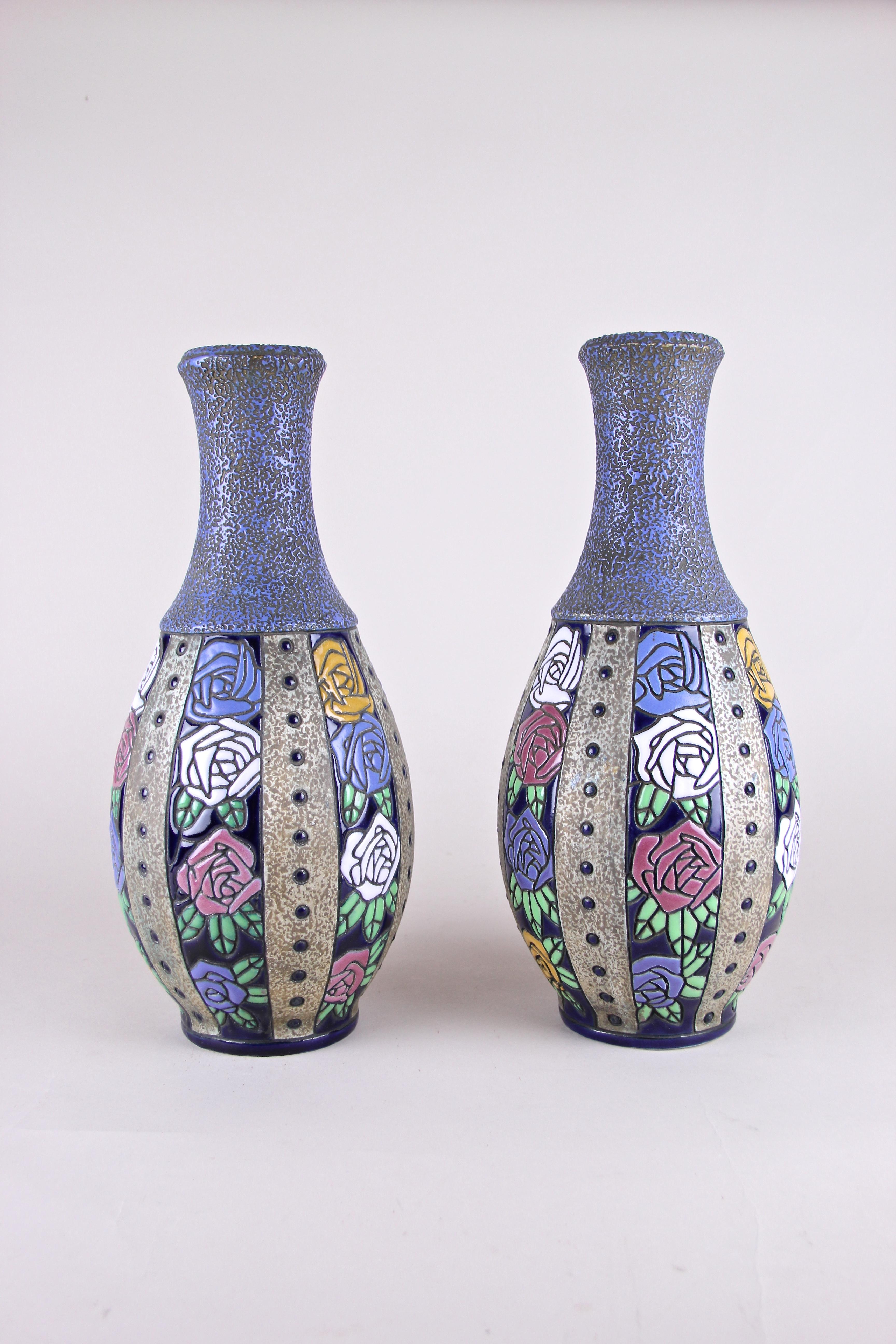 Beautiful pair of Art Nouveau vases by Amphora Czechoslovakia, circa 1915. This great designed vases show a unique design with colorful roses in pink, white, yellow and blue, mixed and splitted in fields of four around the bulbous bodies. The vases