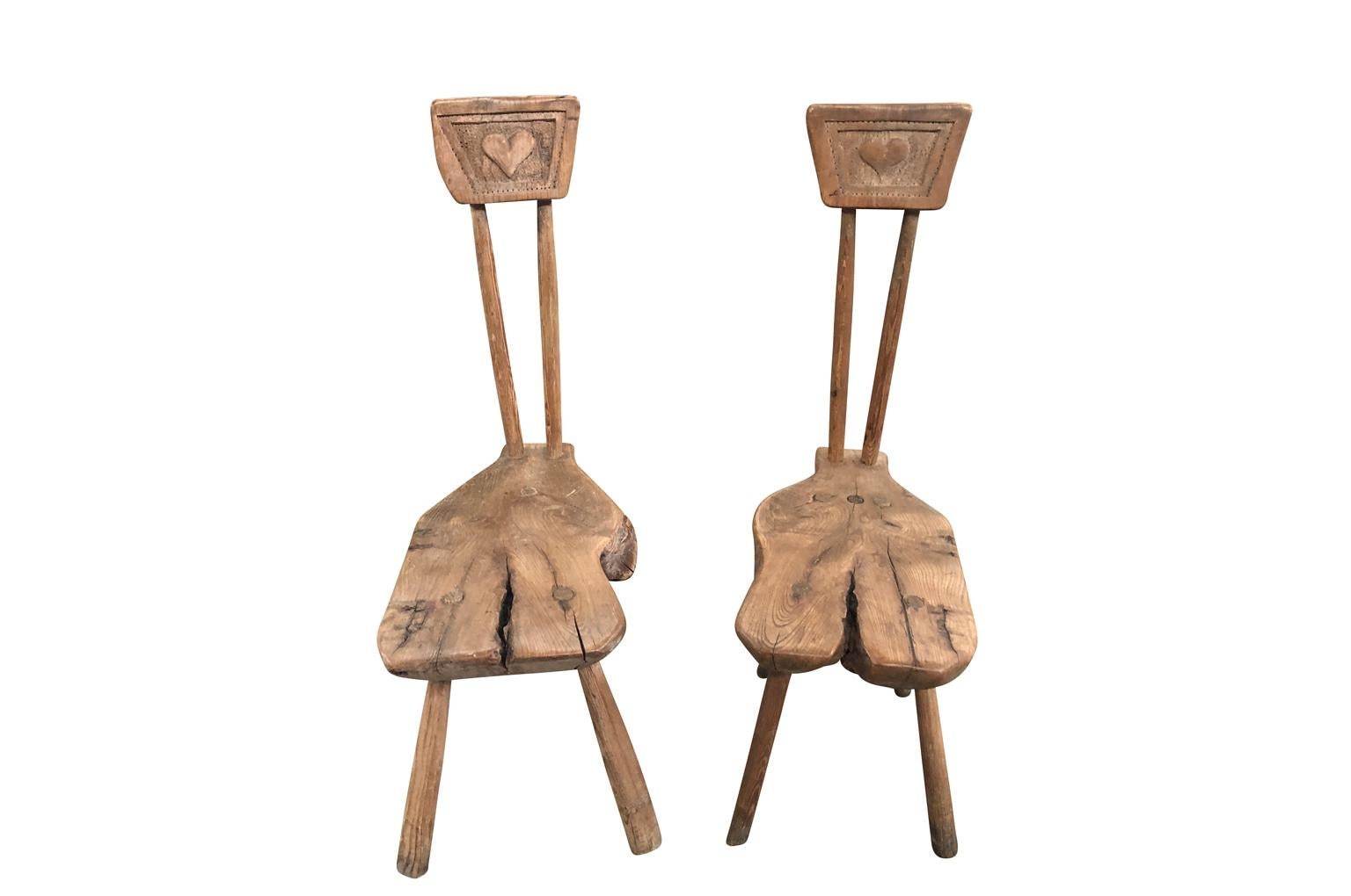 A delightful pair of early 19th century Arte Populaire, Folk Art side chairs from the South of France. Sturdily constructed from elm wood with unique design and charming carved hearts. Wonderful patina. A terrific accent piece for any casual living