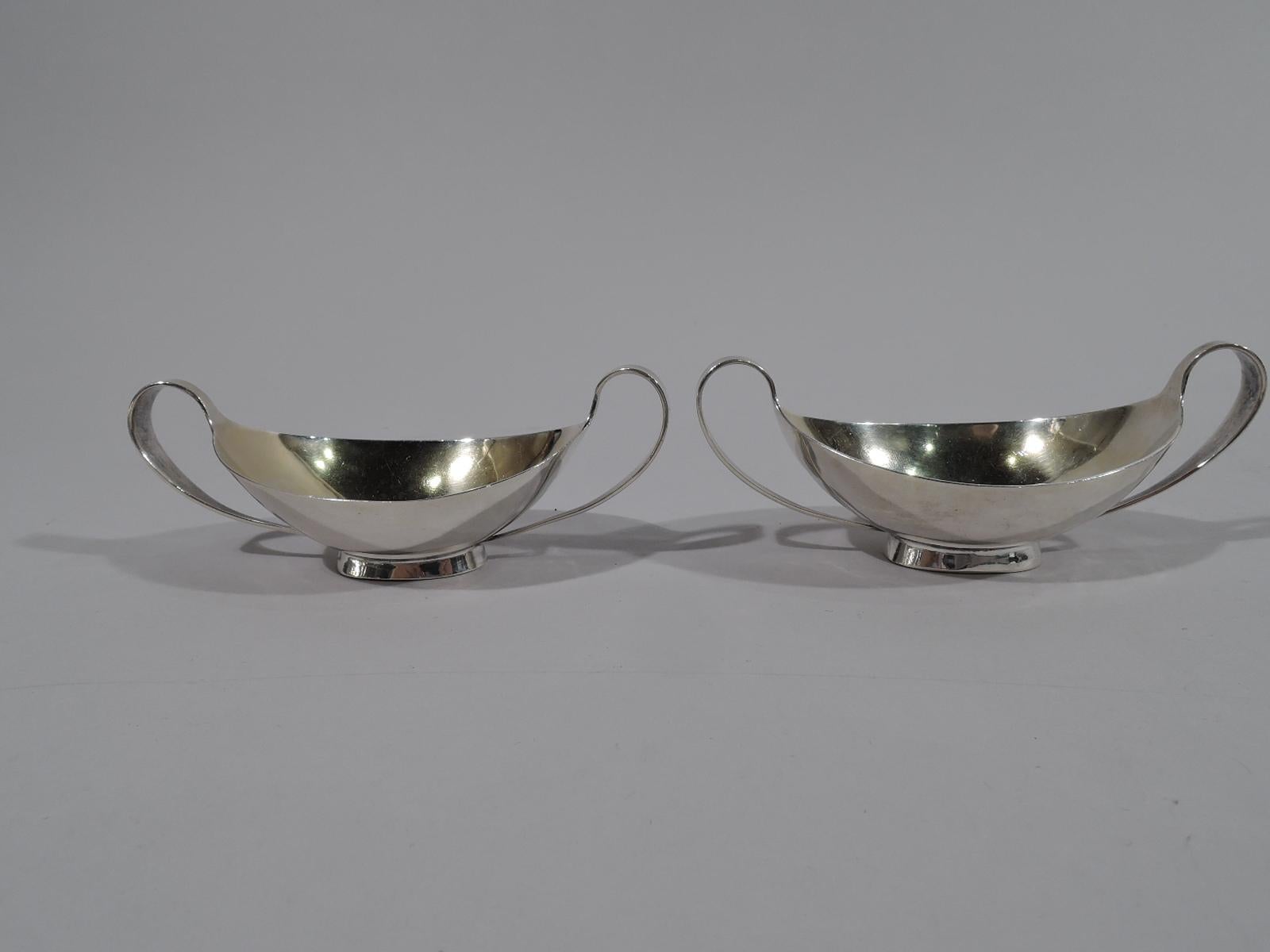 Pair of Classical sterling silver open salts. Made by Arthur stone in gardner, mass. Each: Ovoid with high looping end handles terminating at spread oval foot. Interior gilt washed. Fully marked including initial P, which represents either one