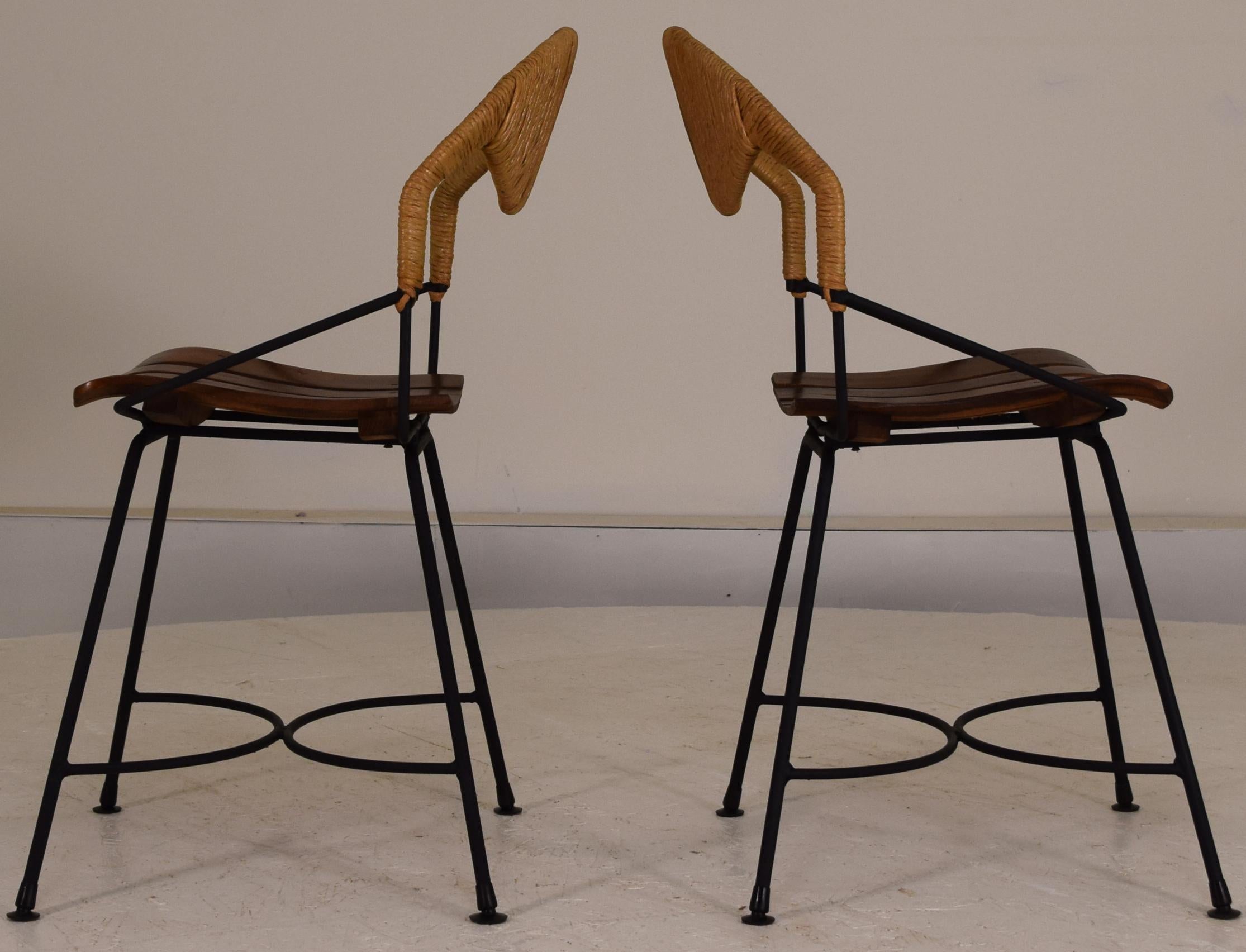 Price is for the set of 2. Modernist chairs, Shaver Howard production. Set of 2 chairs. Beautiful lines of iron and wood slats with fiber rush woven backs. In exceptional condition still with original feet on each leg. Ideal of closed patio or other