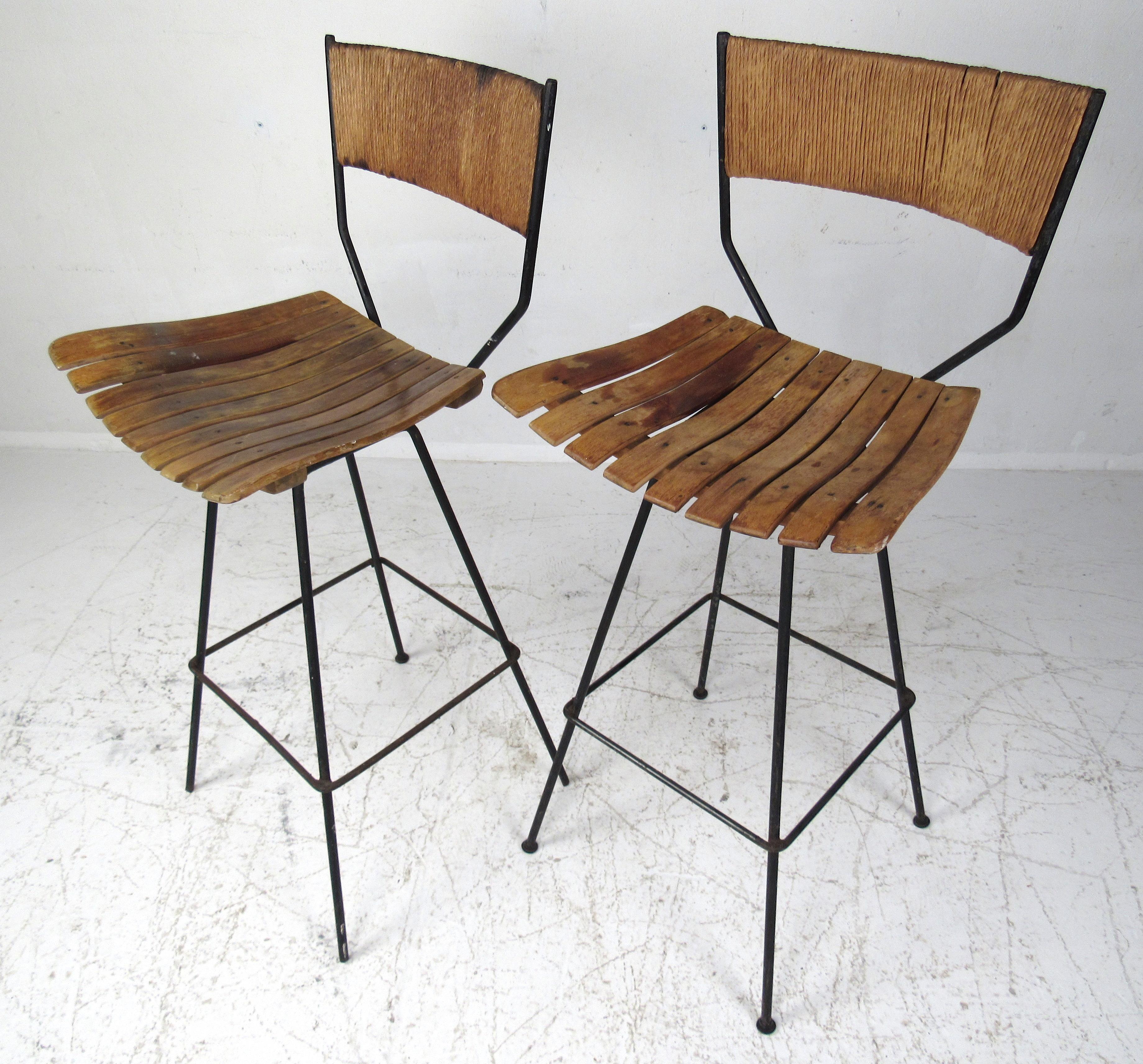Pair of Arthur Umanoff tall swivel bar stools designed for Raymor in the 1960s. These iconic stools feature an iron base with bentwood slatted seats and a woven rush backrest. The perfect addition to the mid-century environment. Please confirm item