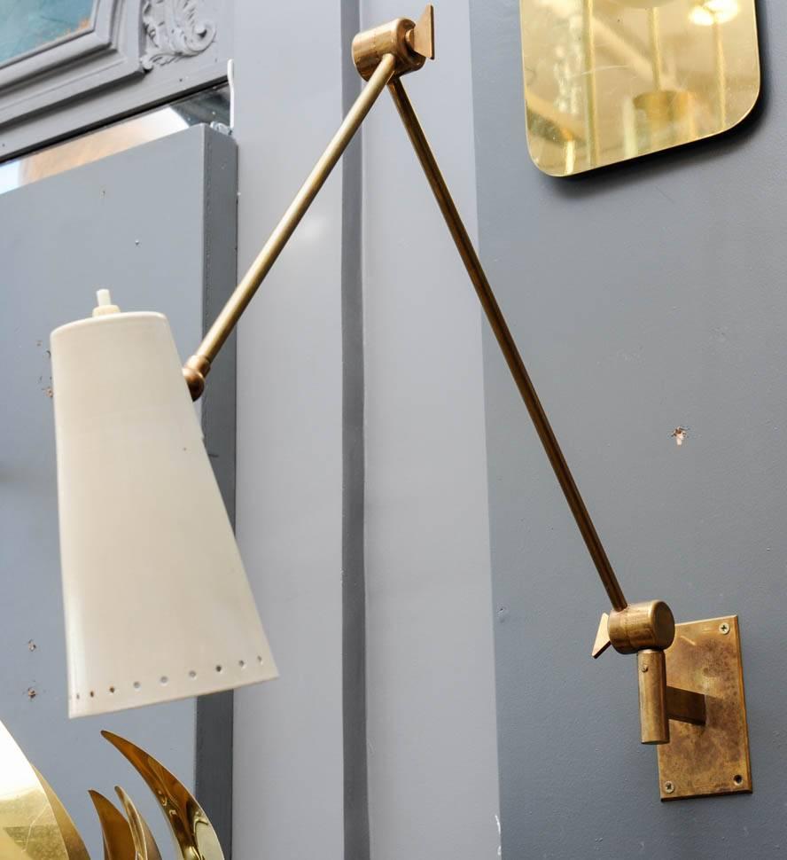 Pair of very chic wall sconces, made of a backplate with Stilnovo stamp, brass arm articulated in three points and a white enameled metal cone with the light switch above it.

The given dimensions the sconces' in the position in the pictures.