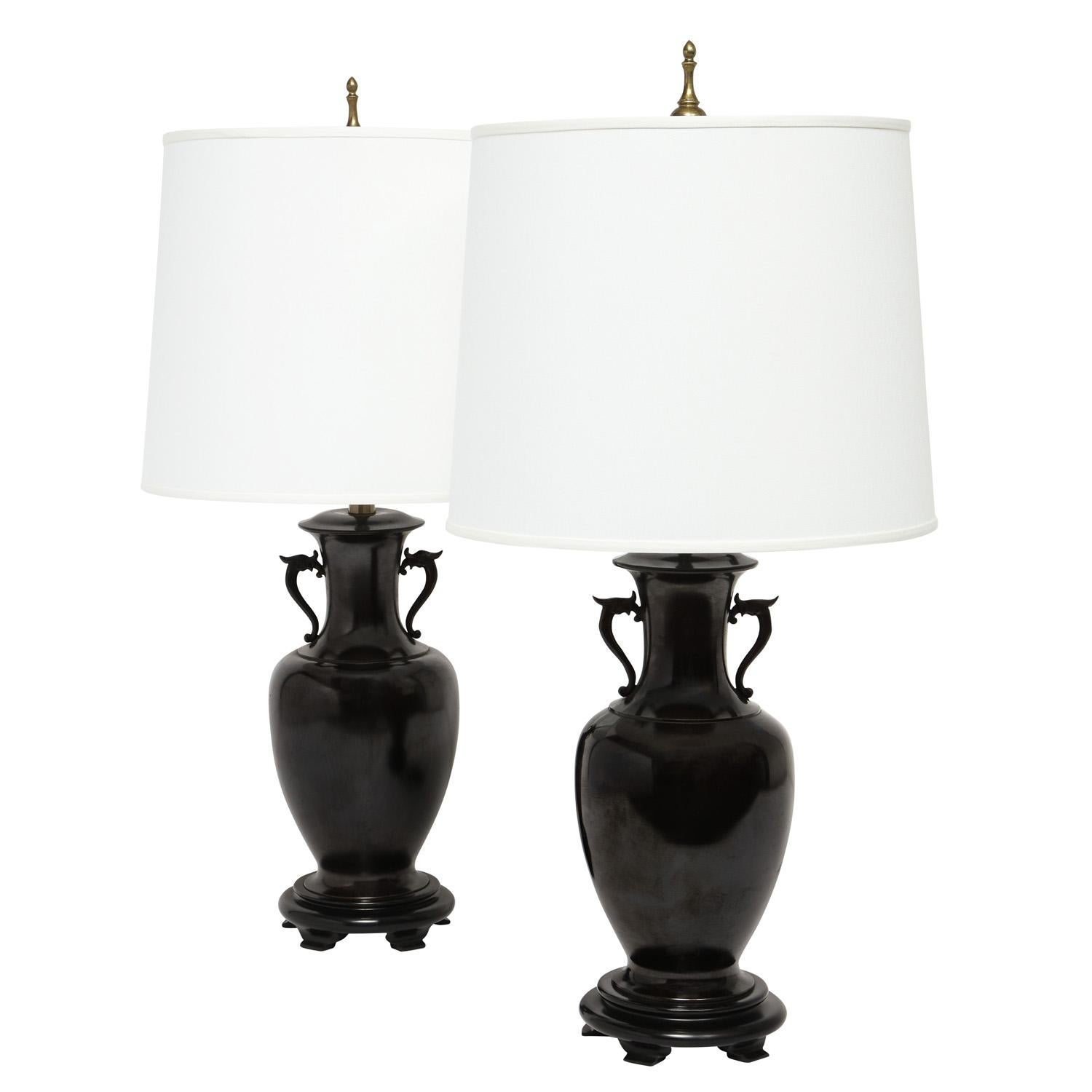 Pair of artisan Asian-style table lamps in gunmetal bronze with dragons on sides and brass hardware on ebonized wood bases, American 1960's. These lamps are beautifully proportioned and very chic.

Shade Diameter: 16 inches
Shade Height: 13