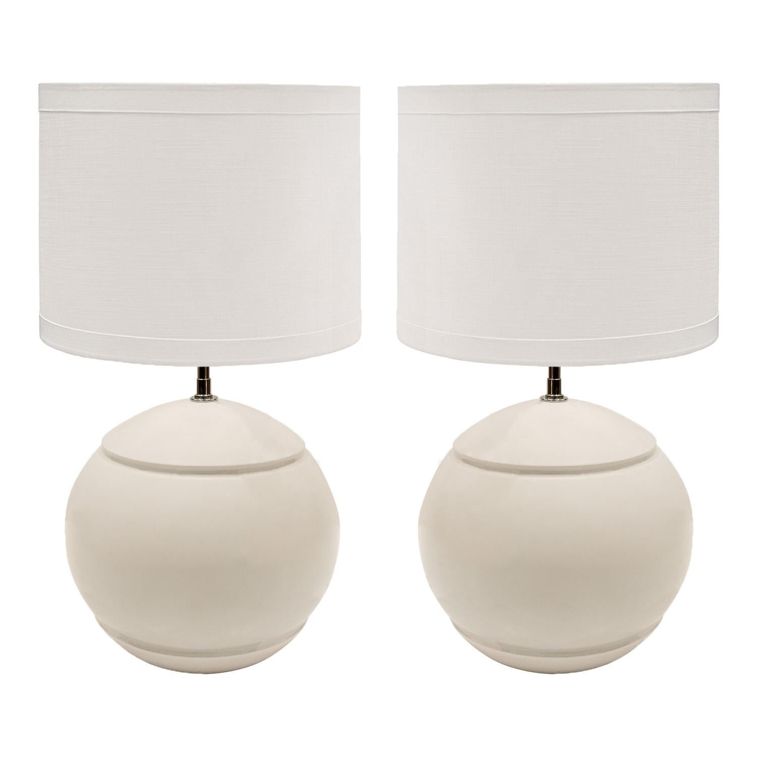 Artisan made white ceramic table lamps, orbs with reveals at top and bottom, with chrome fittings and sockets and silk cords, American 1970's. These lamps are simple yet elegant. Chrome hardware has been polished and replated by Lobel Modern. Newly