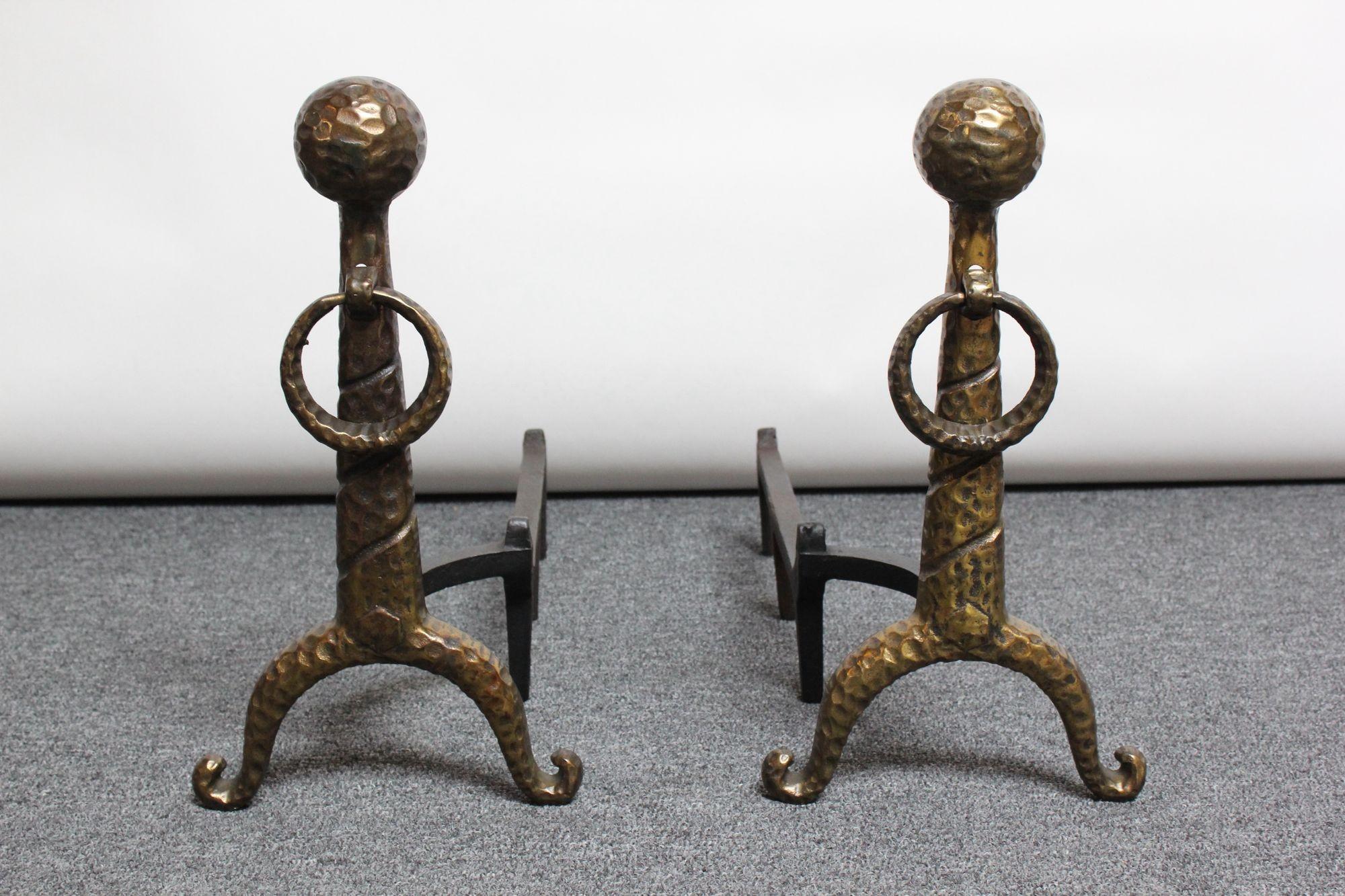 Circa 1940s Arts & Crafts-Style andirons composed of hammered ball and ring cast-brass uprights attached to an iron billet bar.
Very fine, vintage condition with patina/light wear present to the cast-brass; black paint has been touched up.
H: 18.13