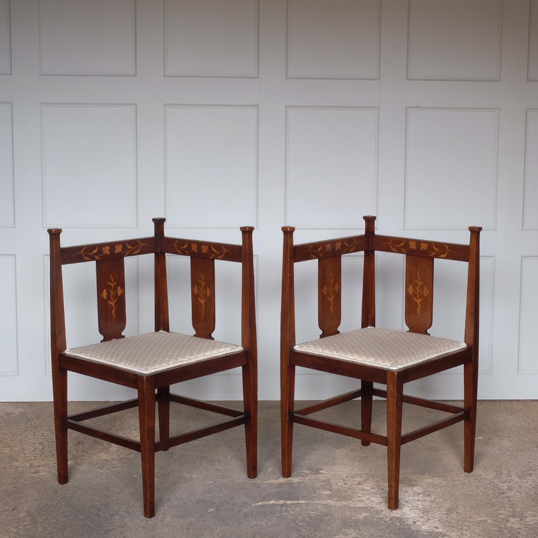 Paire de chaises d'angle en acajou marqueté Arts and Crafts, avec des incrustations de motifs floraux sur les dossiers et des bases d'assise récemment rembourrées, en très bon état.