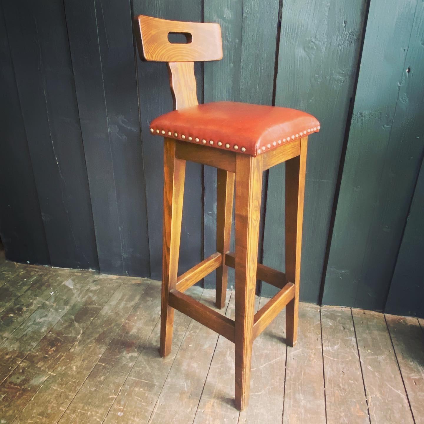 An attractive pair of oak, elm and leather bar stools with stud detail. The curved back with hand cutout and gentle wave like carving to the upright support. The square seat with handsome stud detail. Standing on square tapering legs joined by