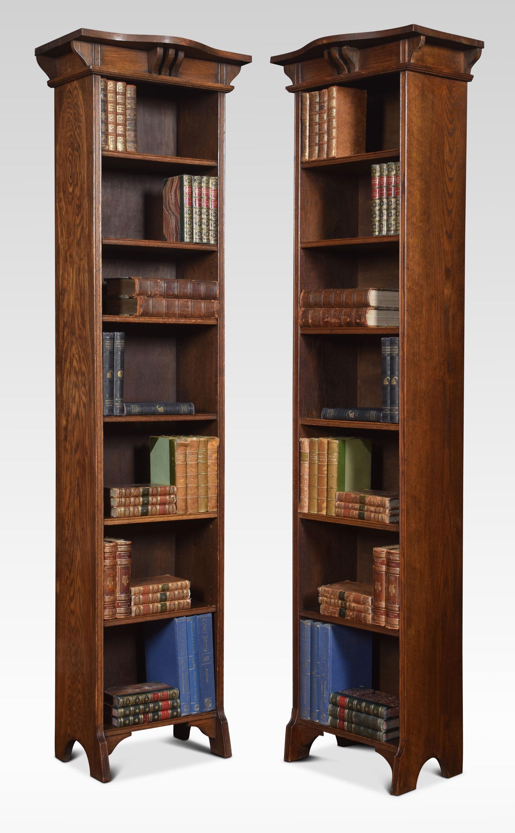 Pair of Arts & Crafts oak open narrow bookcases with serpentine canopy tops above shelved interior one bookcase having fully fixed shelves the other having fixed and adjustable shelves. All raised up on bracket feet.
Dimensions:
Height 71