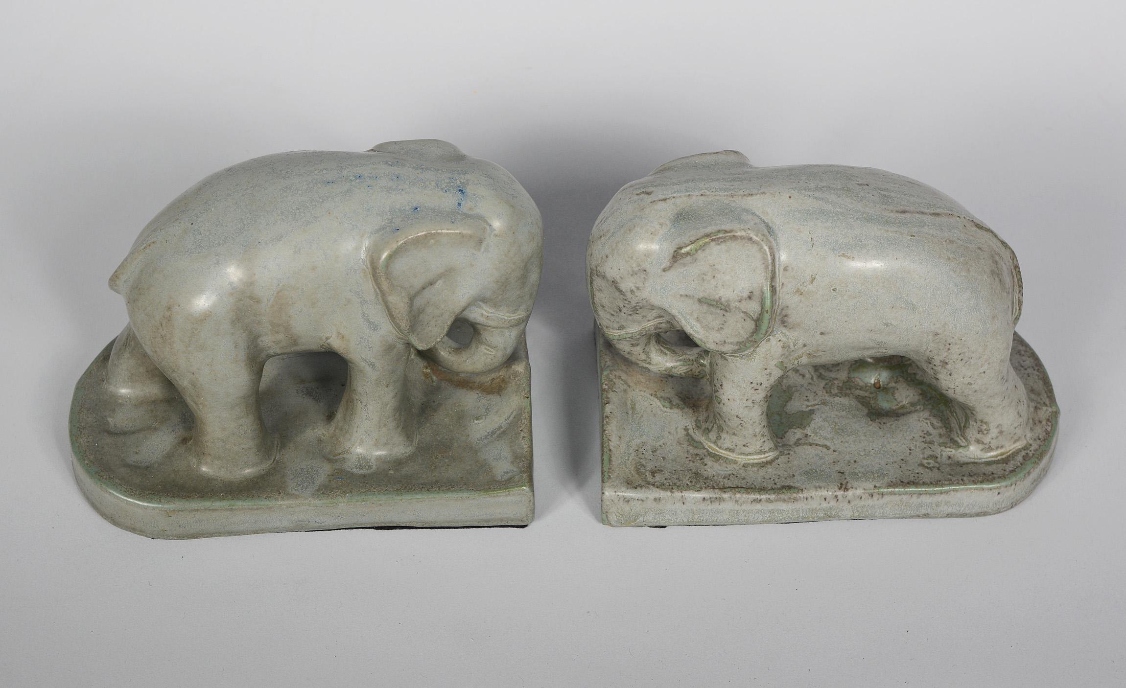 Pair of Arts and Crafts period ceramic elephant bookends. These are not marked. They have in the past been attributed to Monmouth Pottery. These have a great glaze with green mottling on the mainly grey field. There is a tiny glaze flake on the end