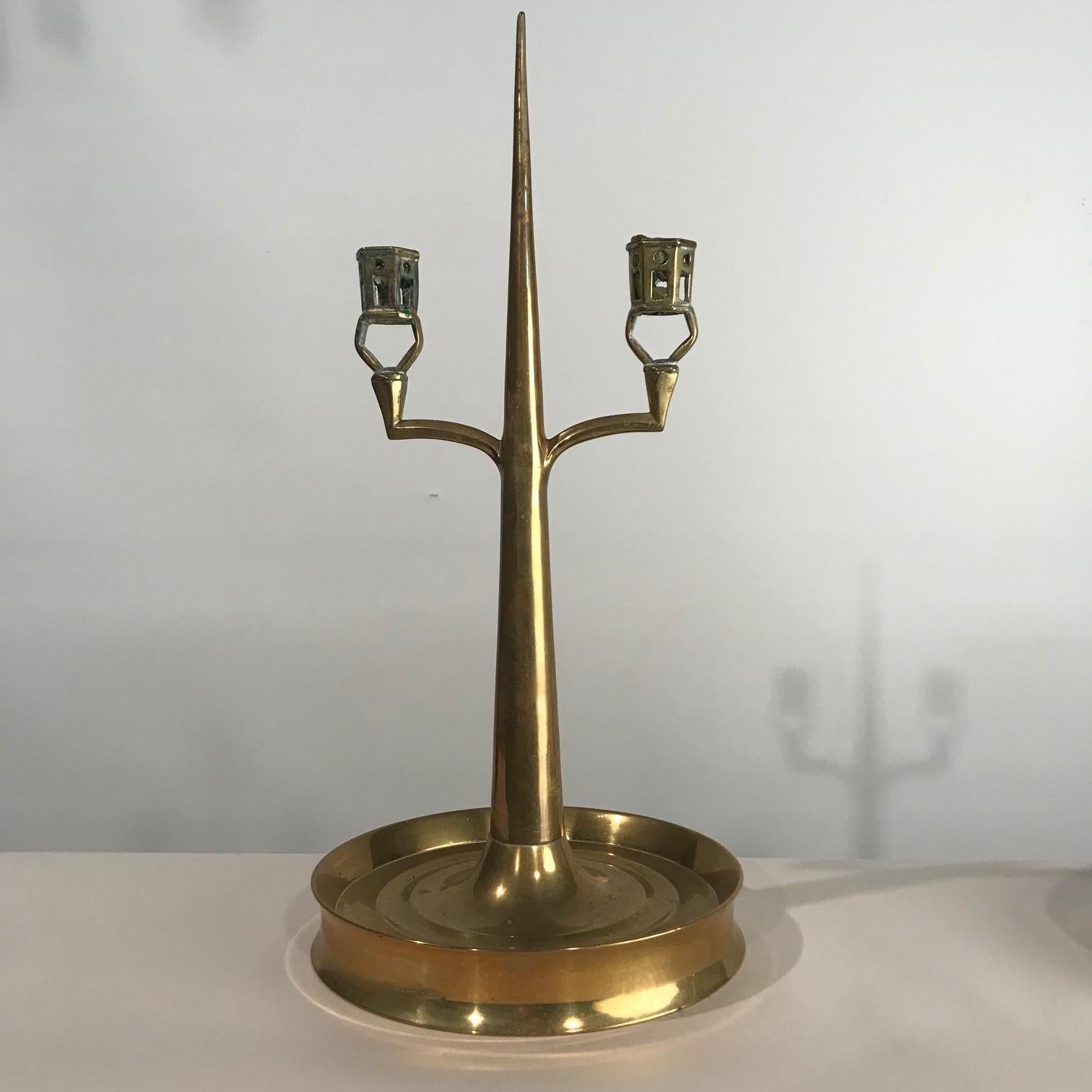 This unusual pair combine an Arts & Crafts sensibility with a Gothic twist. Each tapering central spire supports a pair of pierced hexagonal open candleholders. The round base is turned and dished. This pair has been made by a skilled metalworker in
