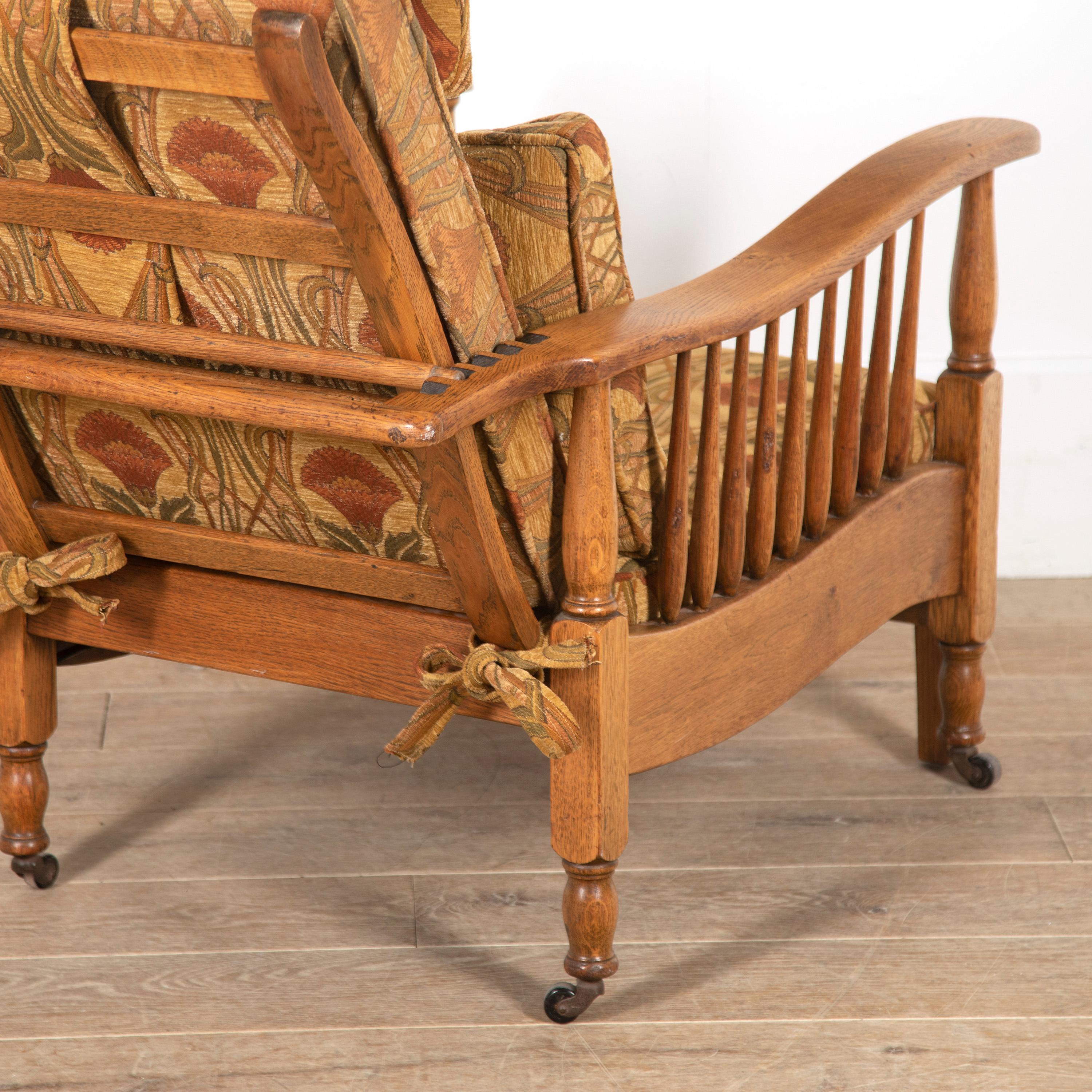 Pair of Arts & Crafts Morris style oak recliner armchairs. 

These armchairs feature decorative extending footrests that are in great working condition for their age. 

Both armchairs have a simple yet elegant form with a great, golden patina