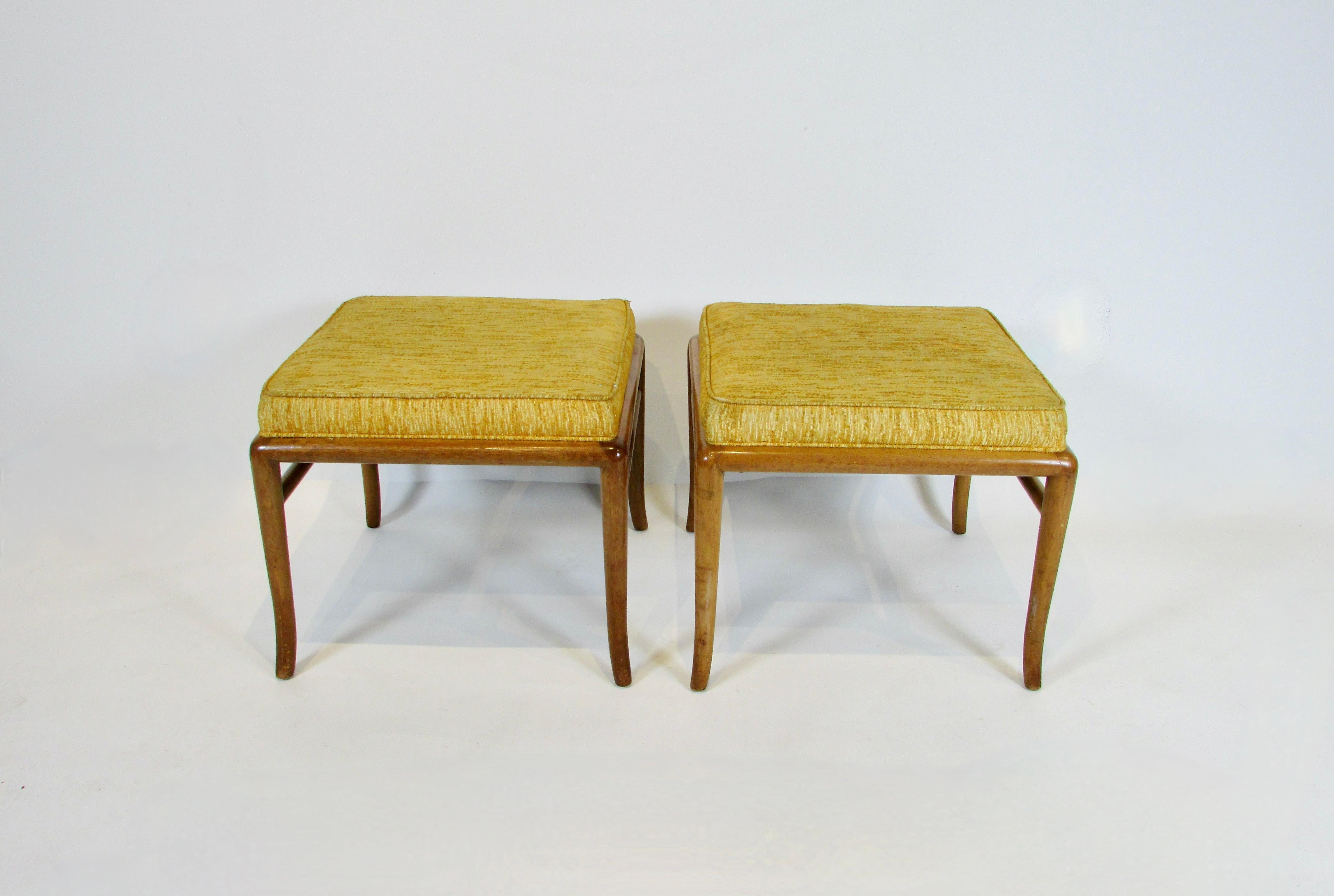 As found original pair of petite stools designed by Robsjohn Gibbings for Widdicomb Furniture mid 1950s . Square walnut frame with classic Gibbings round legs curving out ward as they reach the floor . 
Square upholstered seat is in its original