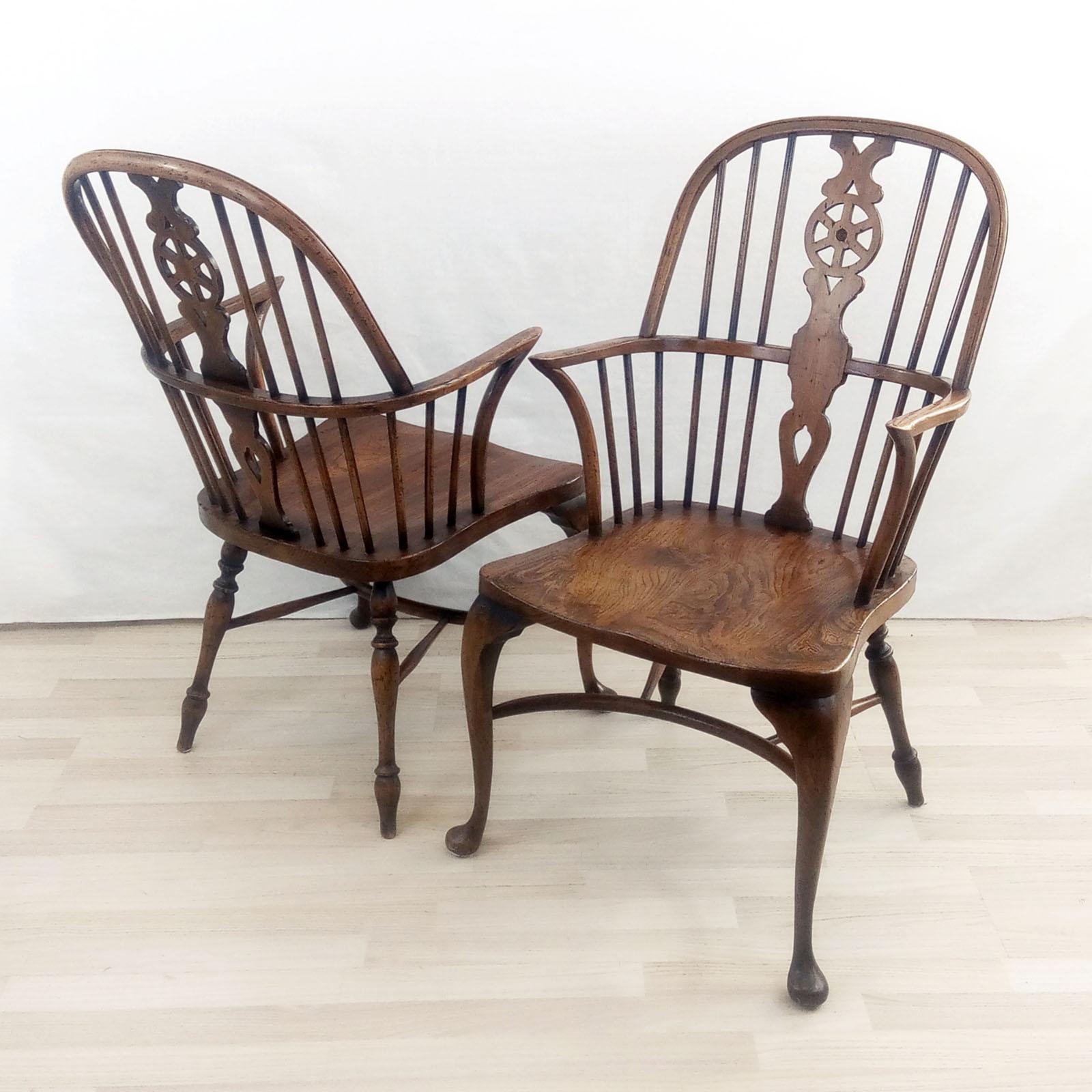 A pair of ash & beech wheelback Windsor armchairs with cabriole leg. Backs and legs made of beech and the seats made of ash. The front legs are of cabriole design, back legs turned, supported with a crinoline stretcher. Original label under the seat