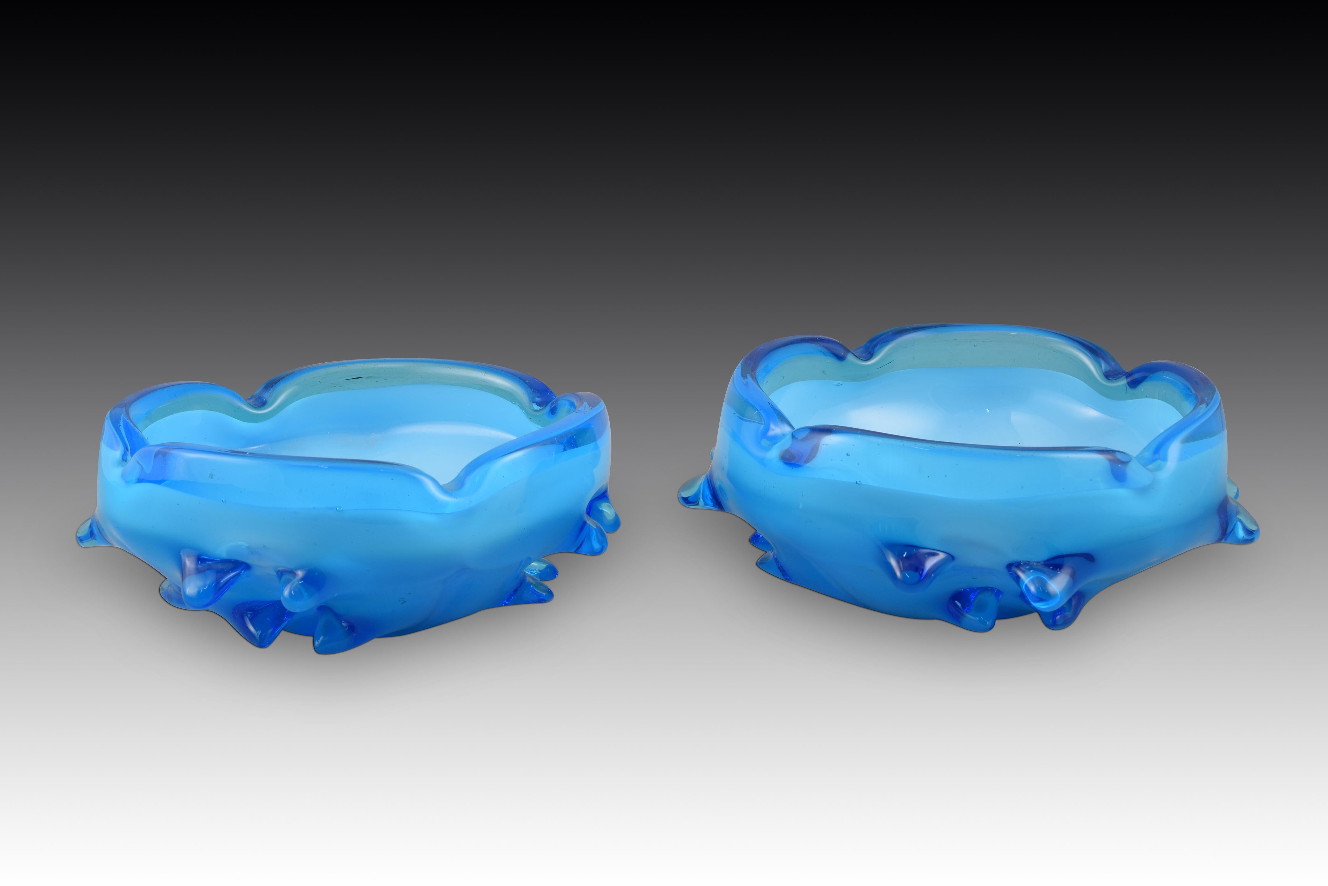 Paar Aschenbecher. Blaues Glas. Murano, Italien, 20. Jahrhundert. 
Zwei Glasaschenbecher, die zwei Blautöne kombinieren und außen mit einer Reihe von dicken Vorsprüngen oder Stacheln am Boden verziert sind. Aufgrund der Form und der Qualität des