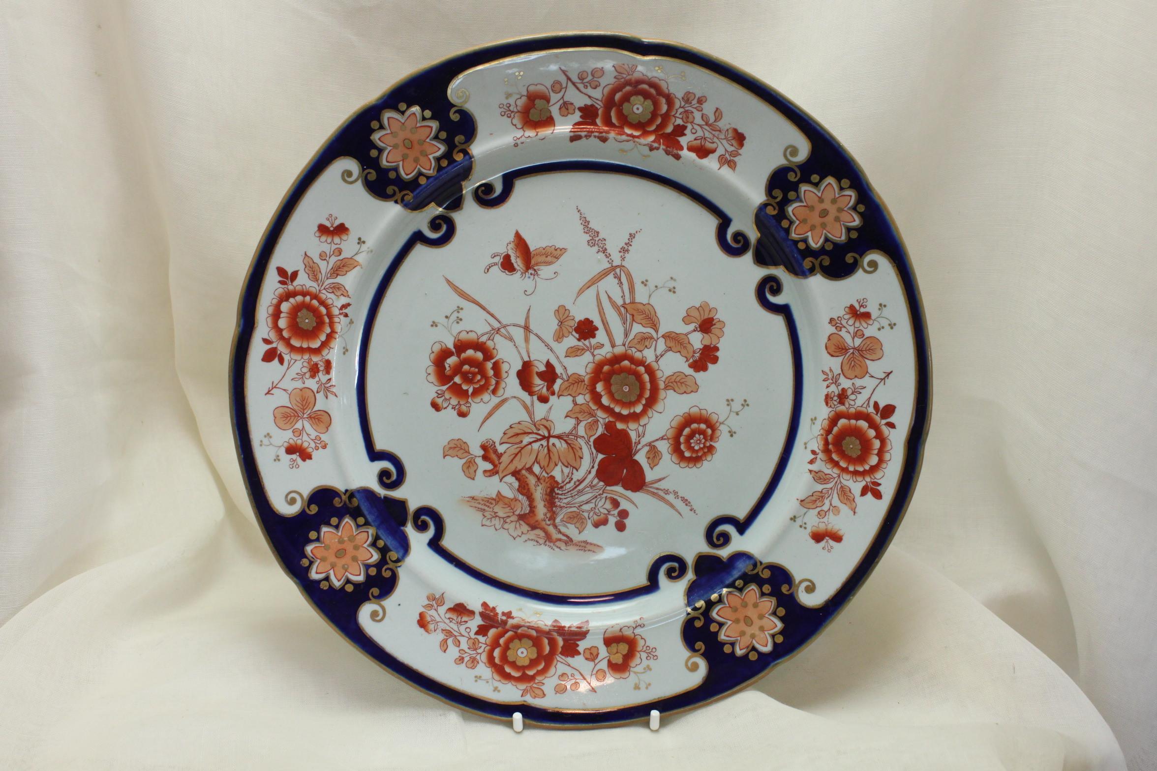This pair of Ashworth's Ironstone plates are decorated with their hand coloured and gilded pattern 3/792 done using the Imari palette of underglaze blue, iron red and gold. To the centre, floating above a flower laden gnarled tree stump is a