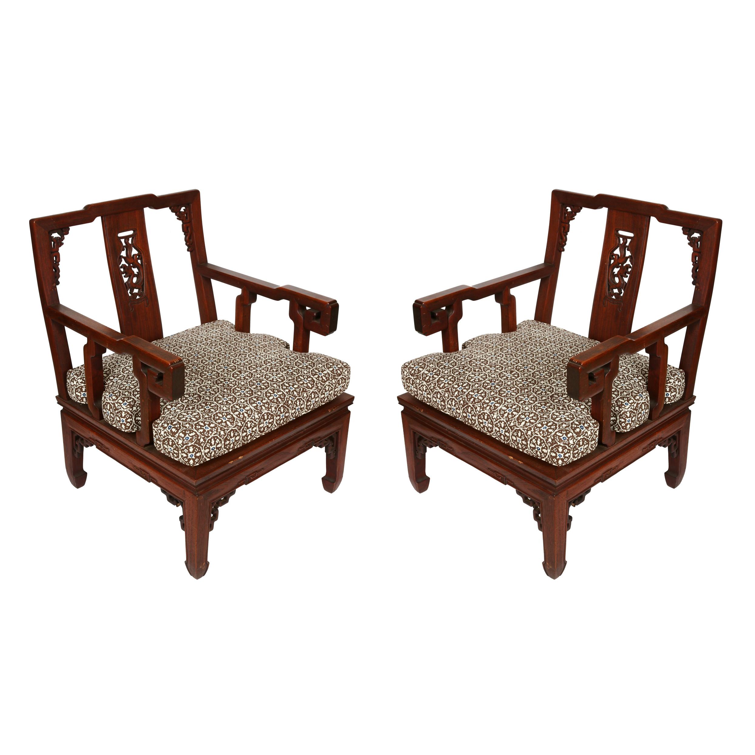 A pair of Asian carved hardwood chairs with tailored cushions.