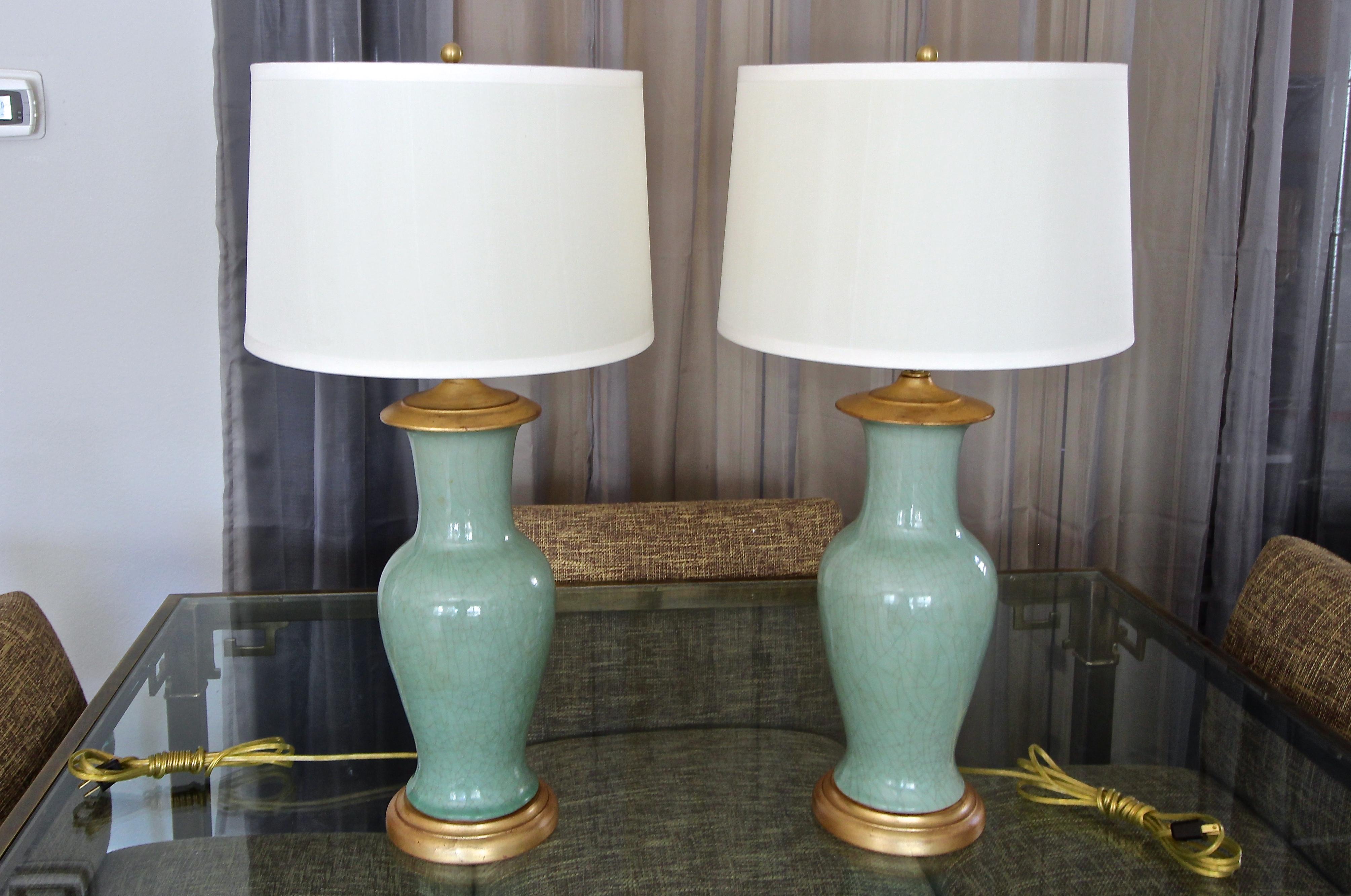 Pair of Asian celadon green crackle glaze porcelain baluster form vases table lamps. Each mounted on gilt turned wood lamp bases. Newly wired with new double cluster pull chain brass sockets. Porcelain vase portion is 16