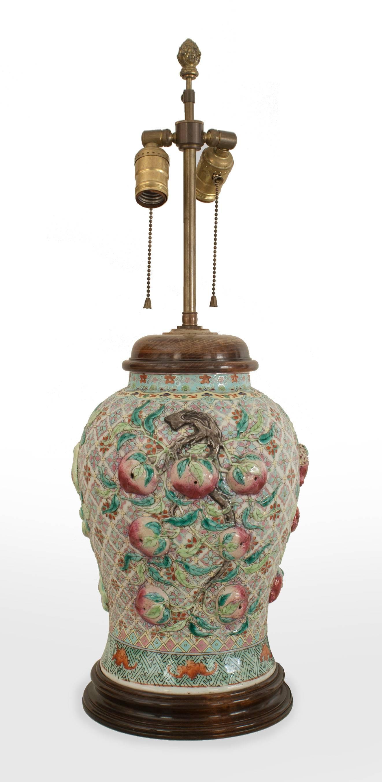 PAIR of Asian Chinese style (20th century) large ginger jar shaped porcelain lamps with a green background and fruit in relief having a teak round base and top.
 