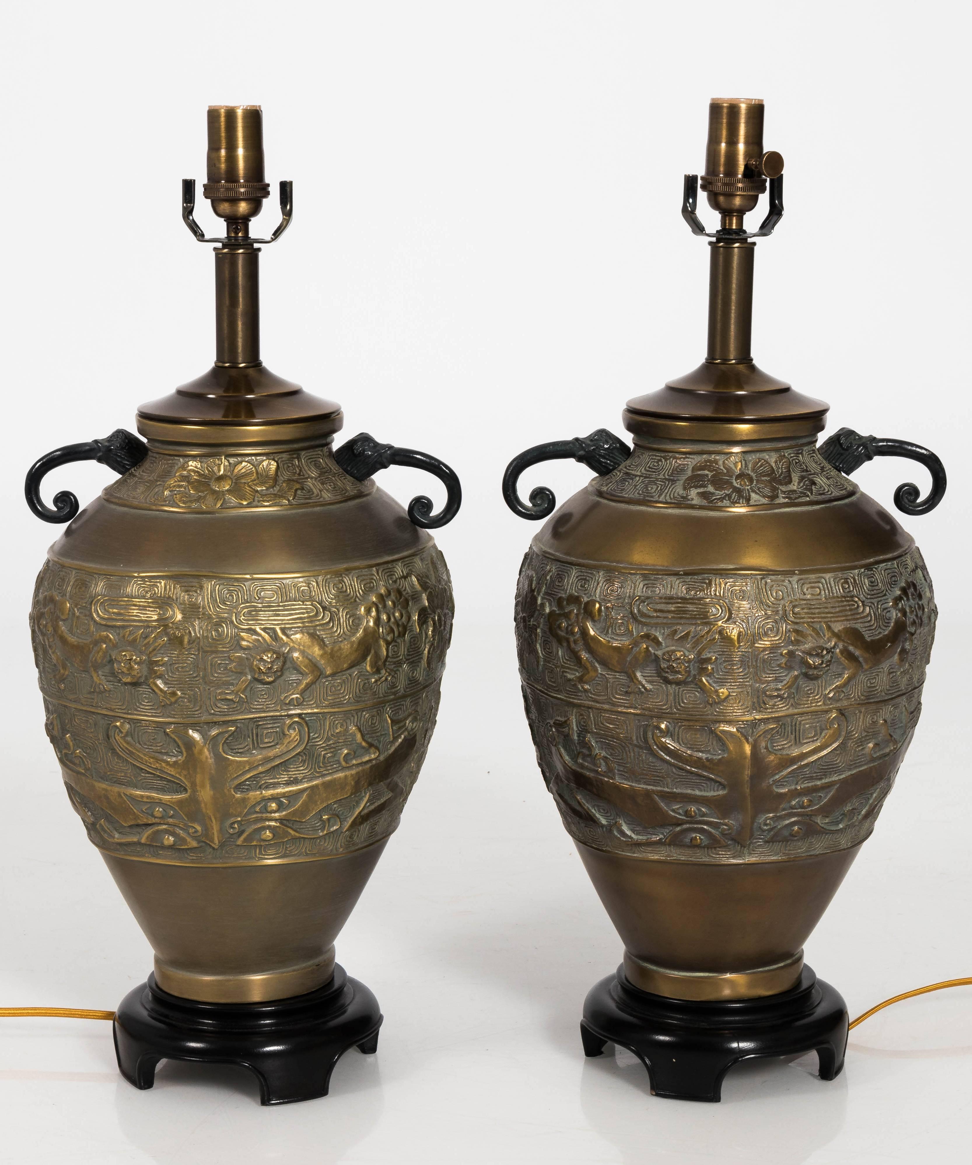 Pair of Asian influenced hammered brass table lamps. Painted black wood bases. Newly rewired. Each lamp takes one standard bulb. Lampshades not included.