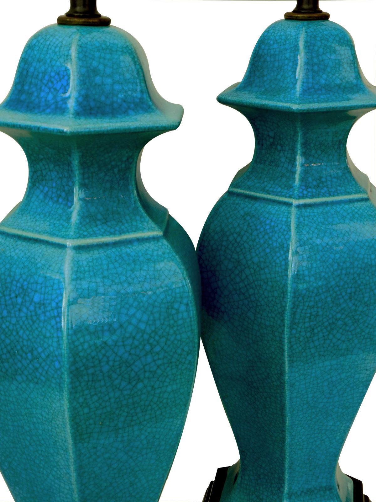 Each shapely octagonal lamp of deep teal crackle glaze raised on carved ebonized wooden bases, measures: height 18