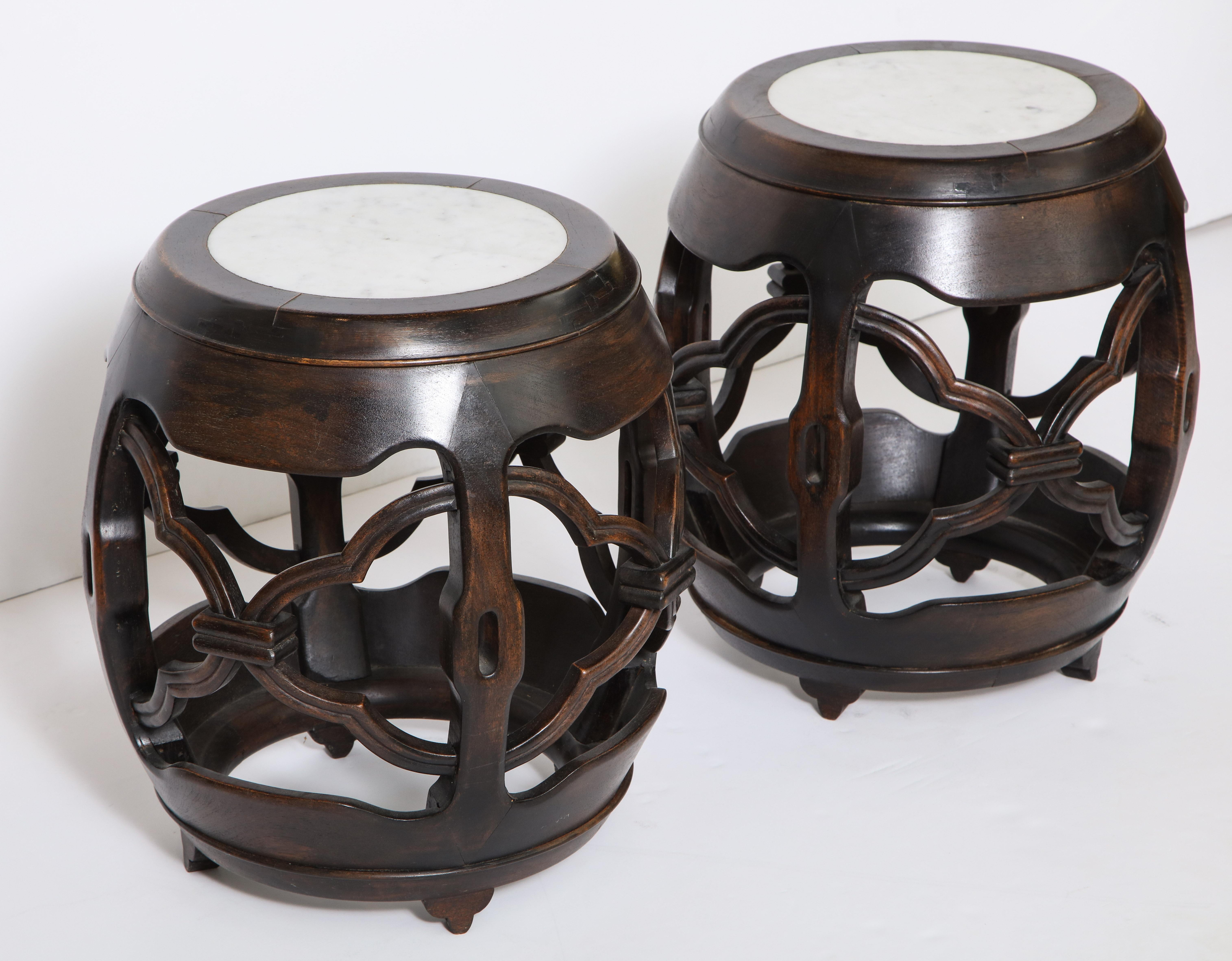 The hand carved barrel form tables each with an inset marble top.