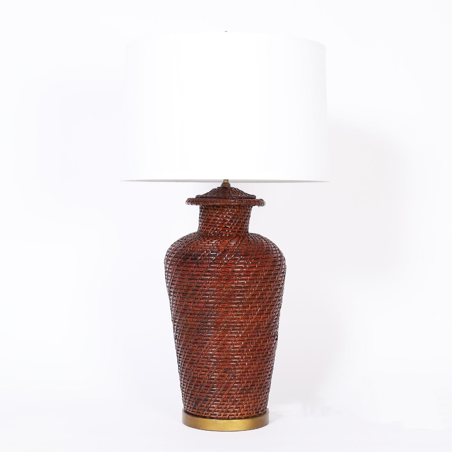 Pair of large scale mid century wicker or reed table lamps stained brown and lacquered with classic form on gold lacquered metal bases.