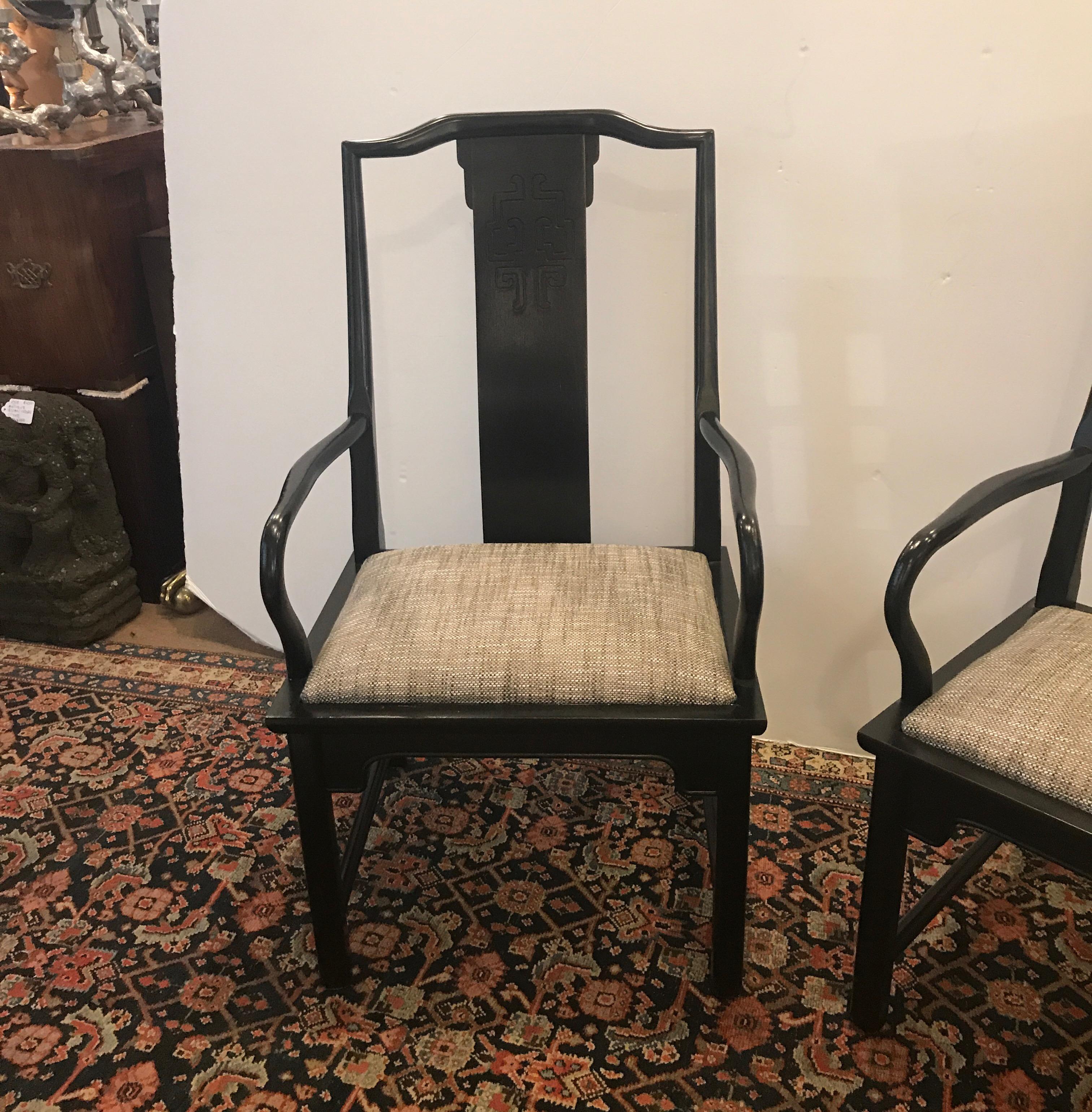 A pair of classically styled Asian style ebonized wood armchairs. The nubby textured woven padded seats contrast nicely to the dark frames. The fabric an be easily changed to suit the rooms interior. The slightly curved backs with a carved Asian