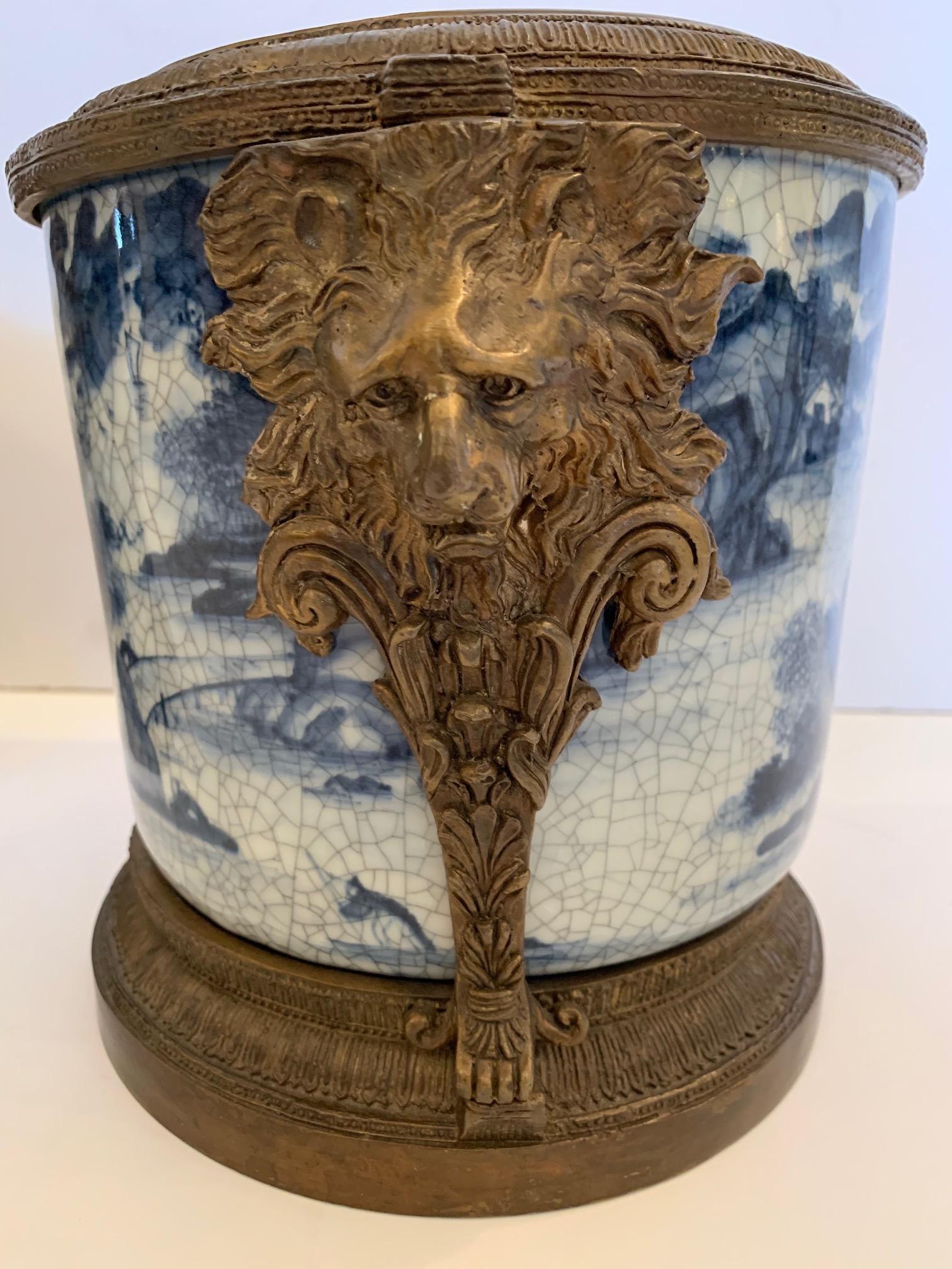 Pair of absolutely beautiful Asian style blue and white cachepots/flower pots having impressive bronze top, bottom and decorative lion heads on the sides.

 