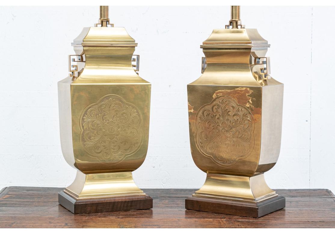 Paire de lampes de table en laiton incisé de style asiatique, en forme de récipient à couvercle, avec des bords nets et des médaillons floraux ciselés à l'avant et à l'arrière, des poignées angulaires ajourées et des montures supérieures. Les bases