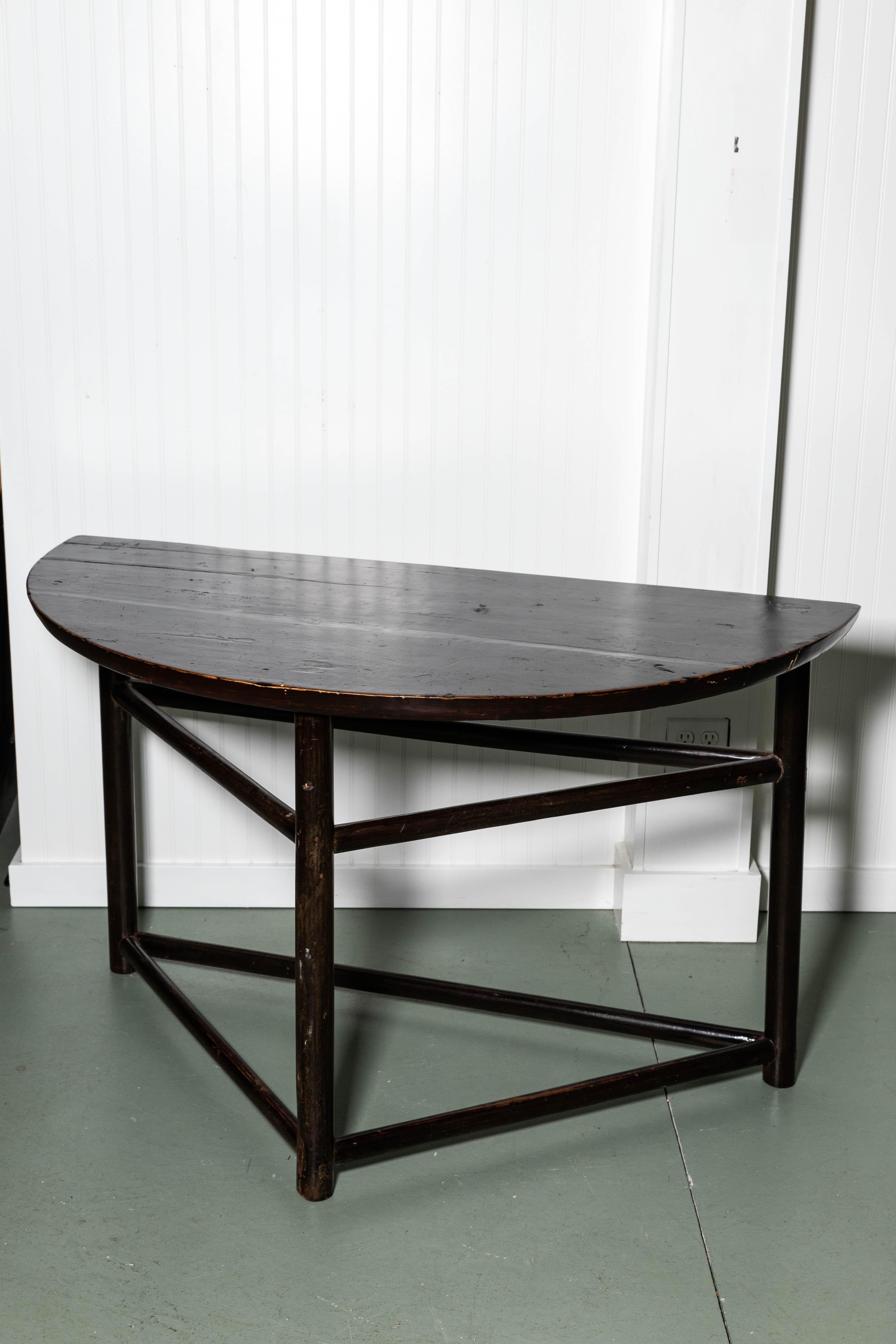 Beautiful Asian style demilune tables, hardwood with black lacquer finish. Three legged table with peg construction. Stretchers on both bottom and three quarter of way up legs. Round straight legs, oval shaped stretchers.