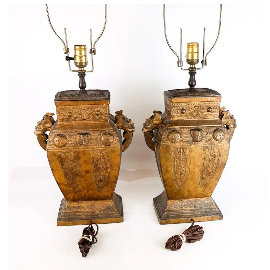 Ein Paar vergoldete Tischlampen, jede fein in klassischer Urnenform gegossen und mit geschnitzten Griffen auf beiden Seiten verziert. Die Korpusse sind reich verziert mit aufwändig geschnitzten und erhabenen Chinoiserie-Motiven, die von der