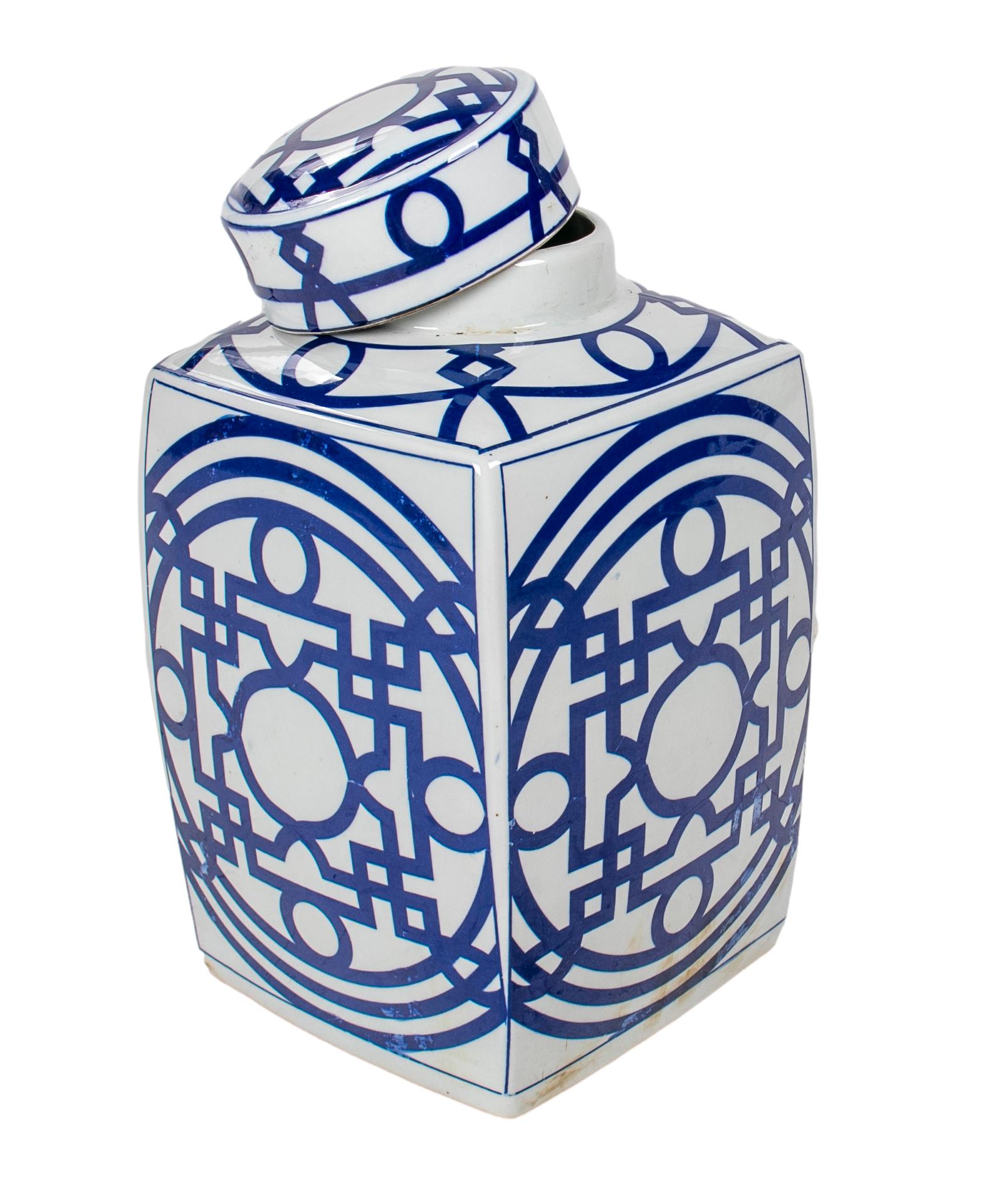 Pair of Asian white glazed porcelain urns with cobalt blue geometric decorations and lids.