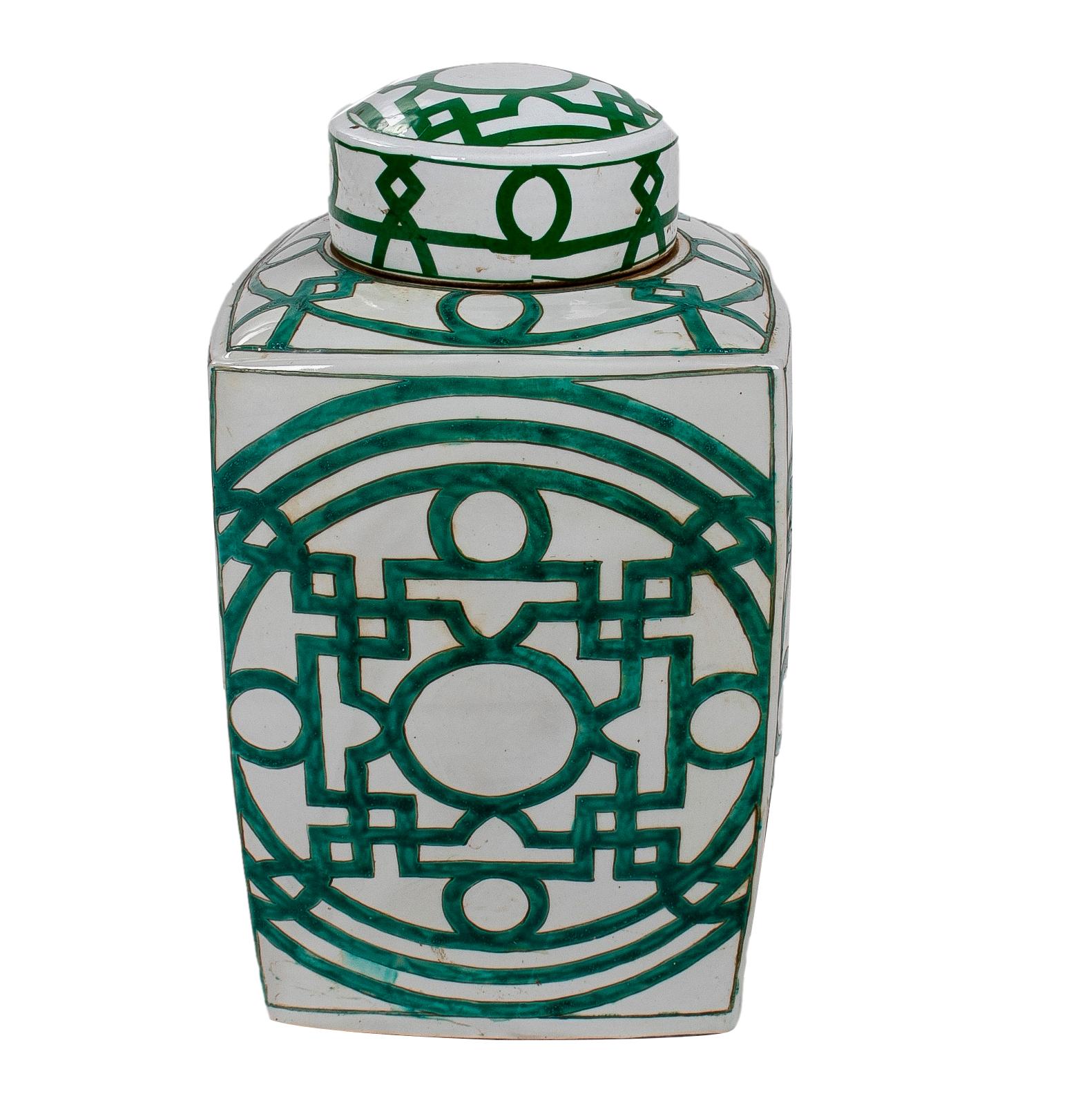 Pair of Asian white glazed porcelain urns with green geometric decorations and lids.
