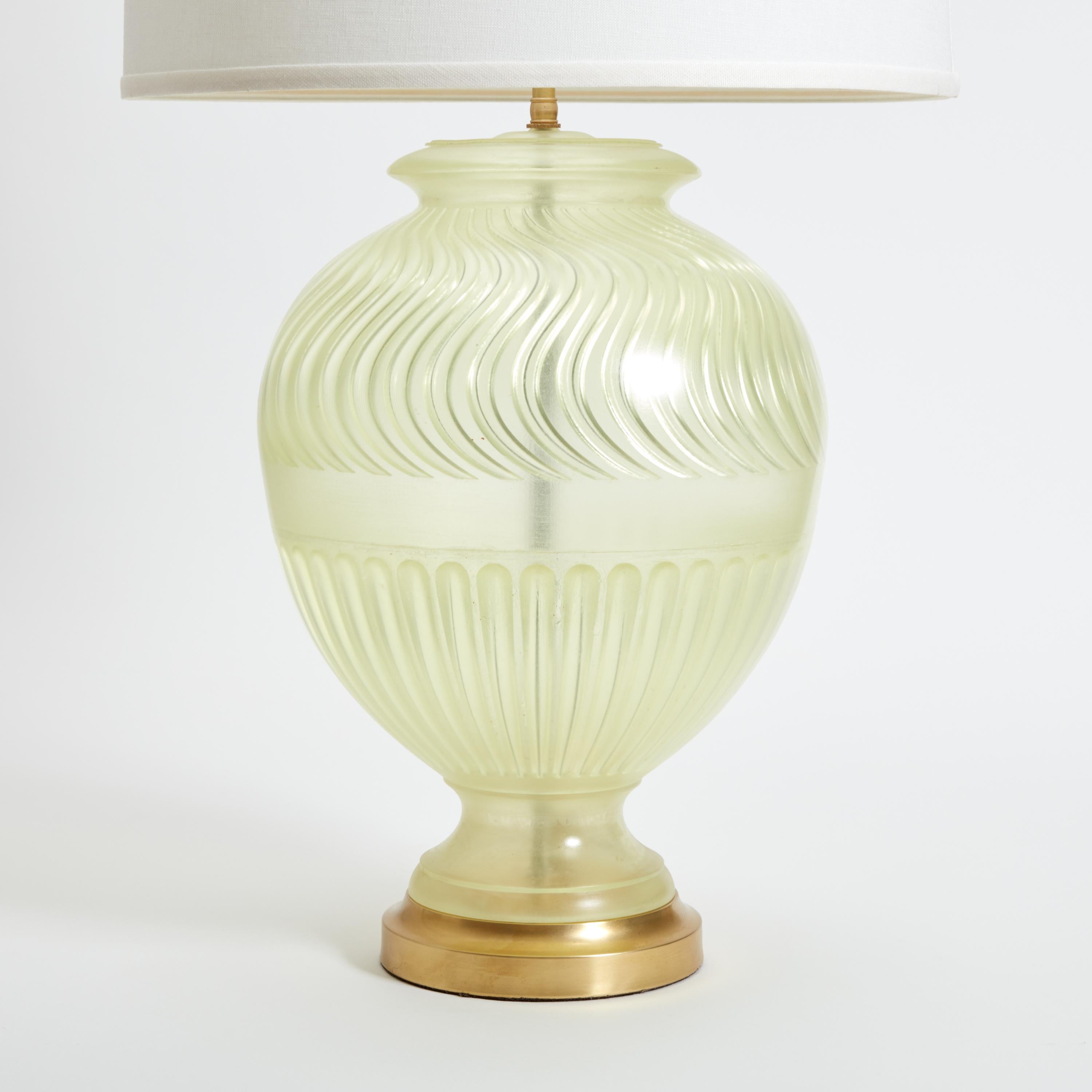 A pair of cast transparent resin lamps that are smooth on the outside with grooved design on the interior, based on an Assyrian vase design. Each lamp has brass details and two sockets. Shades are not included.