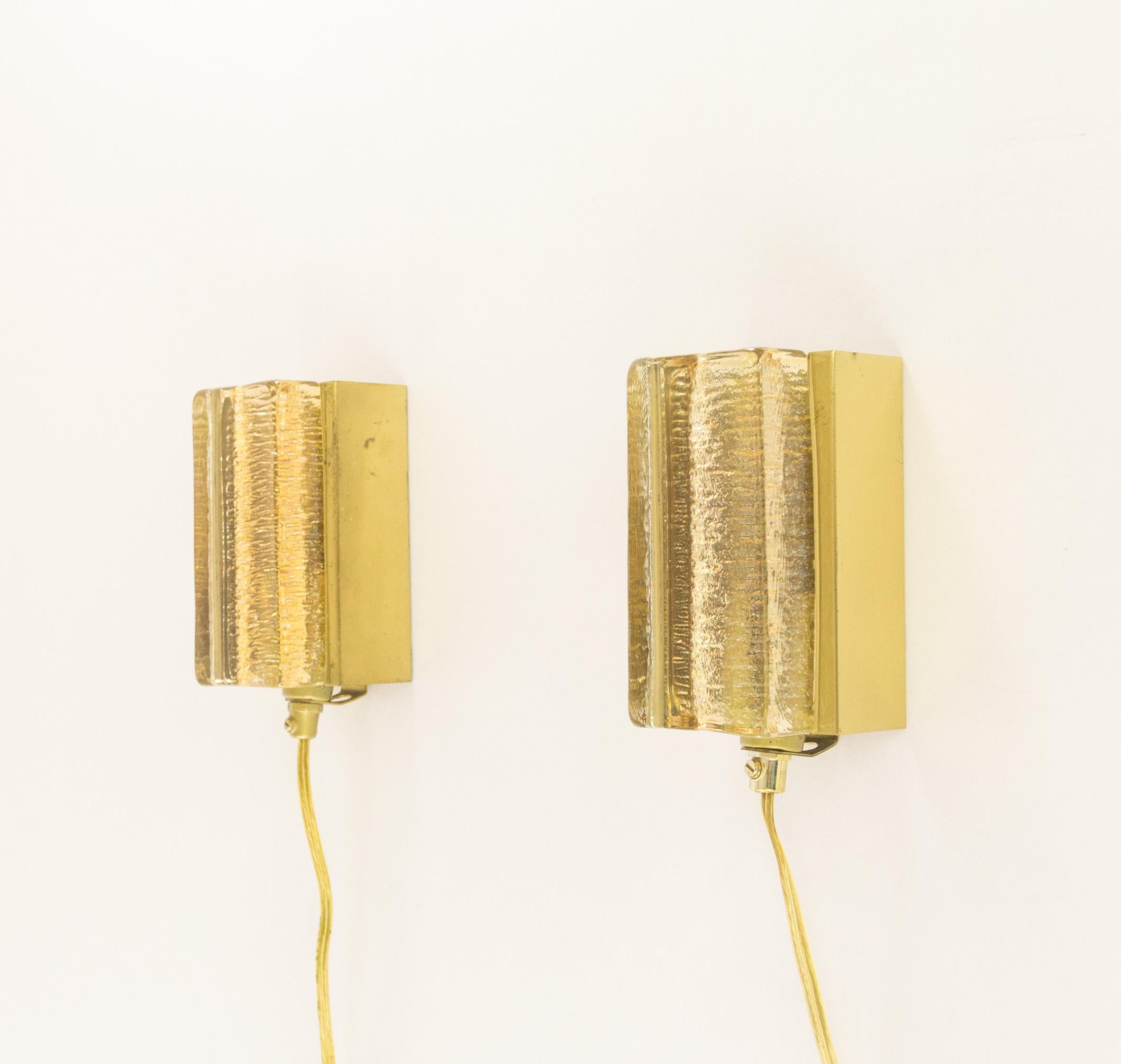 A set of two gold glass and brass Atlantic wall lamps that are produced by Danish lighting manufacturer Vitrika in the 1970s. Both lamps consist of two parts: a solid handmade glass body in gold, and the brass holder.

The condition of the brass