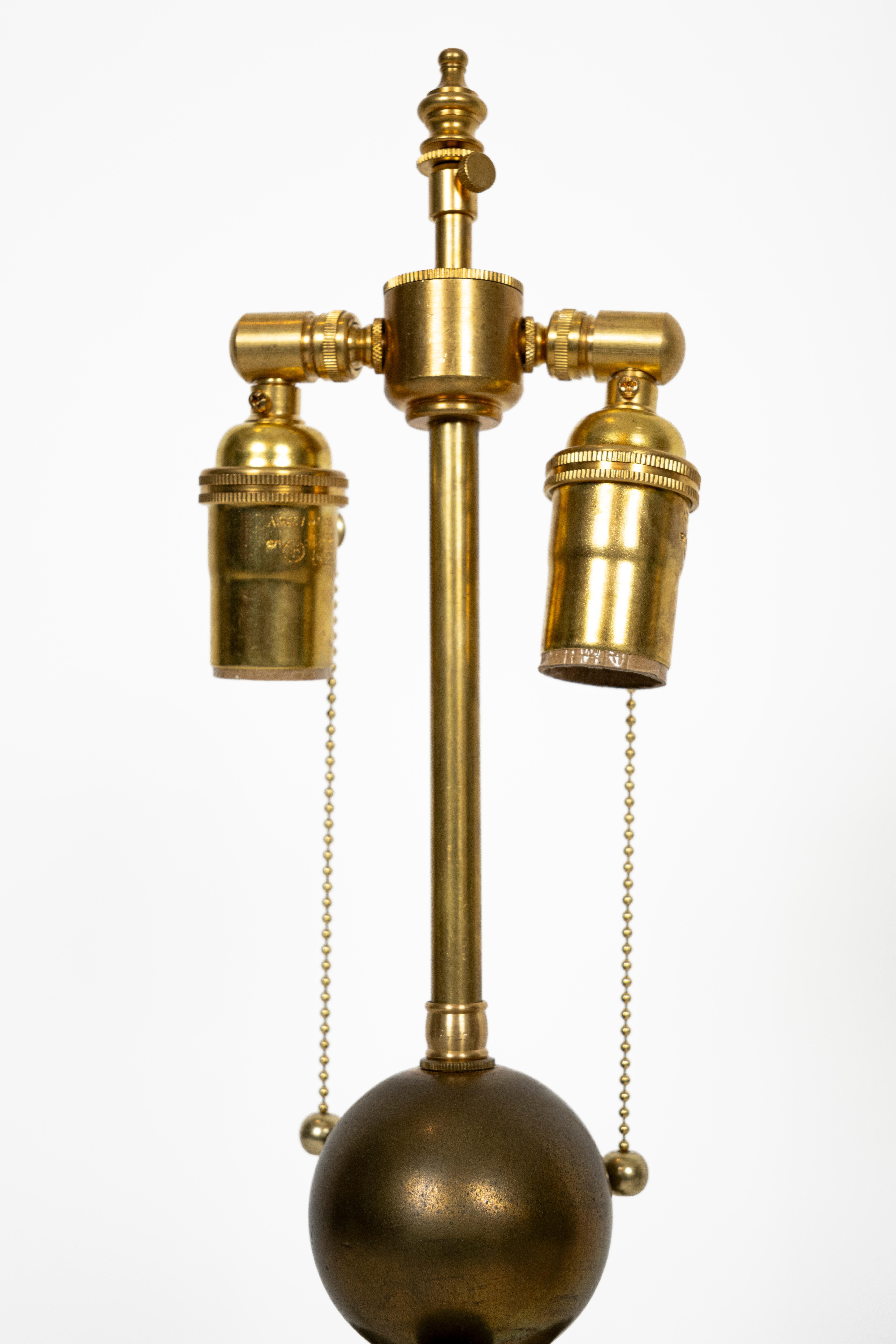 Paire de lampes de table de style néoclassique des années 1920, chacune ornée d'une figure en bronze d'Atlas tenant un globe sur ses épaules, reposant sur une base en marbre blanc sculptée à la main en forme de colonne inversée. Par le fabricant