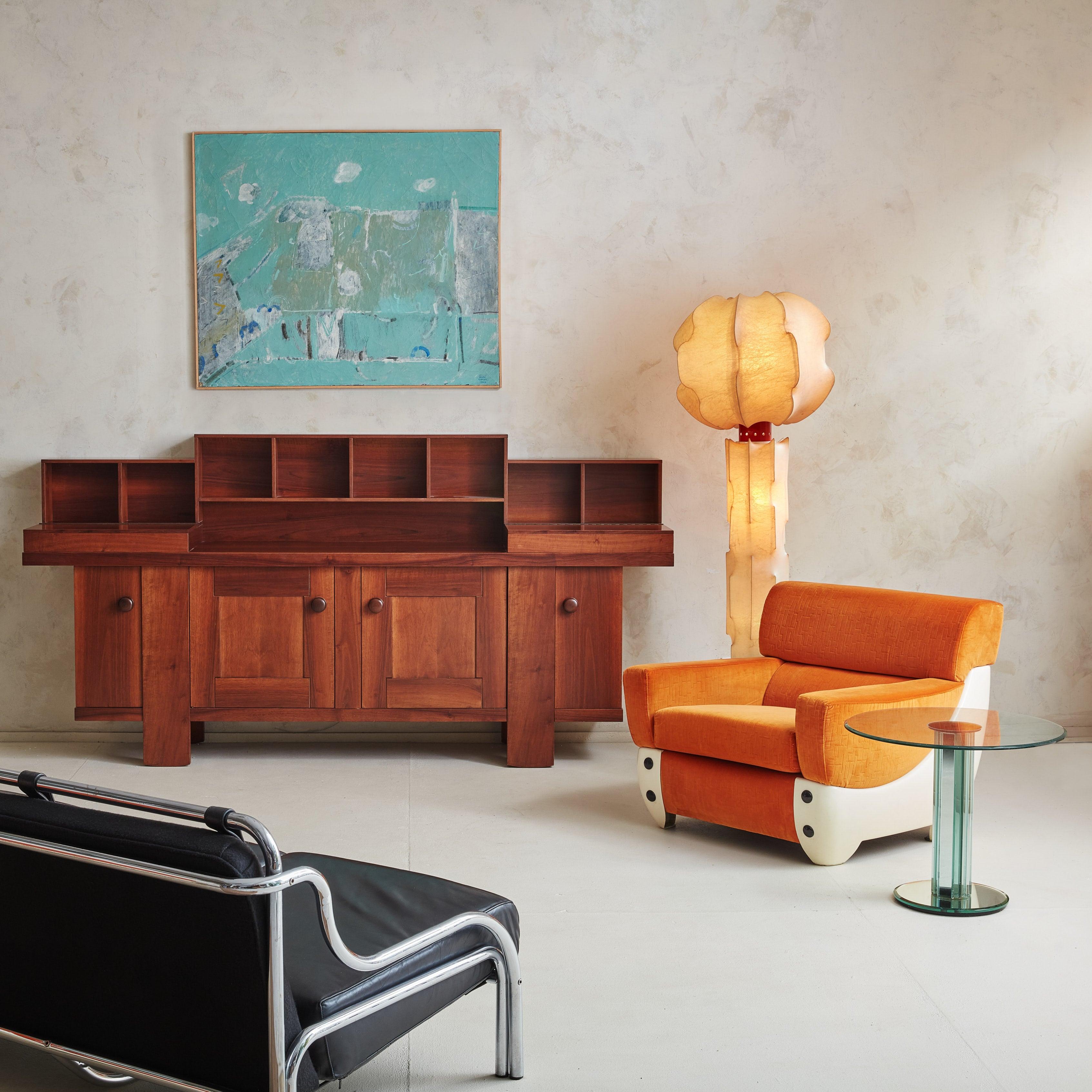 A pair of Atomic Age lounge chairs featuring striking silhouettes with curved fiberglass bases, structured arms, and angled backrests. These sculptural chairs are upholstered in original vibrant, tangerine hued fabric. Subtle geometric patterns
