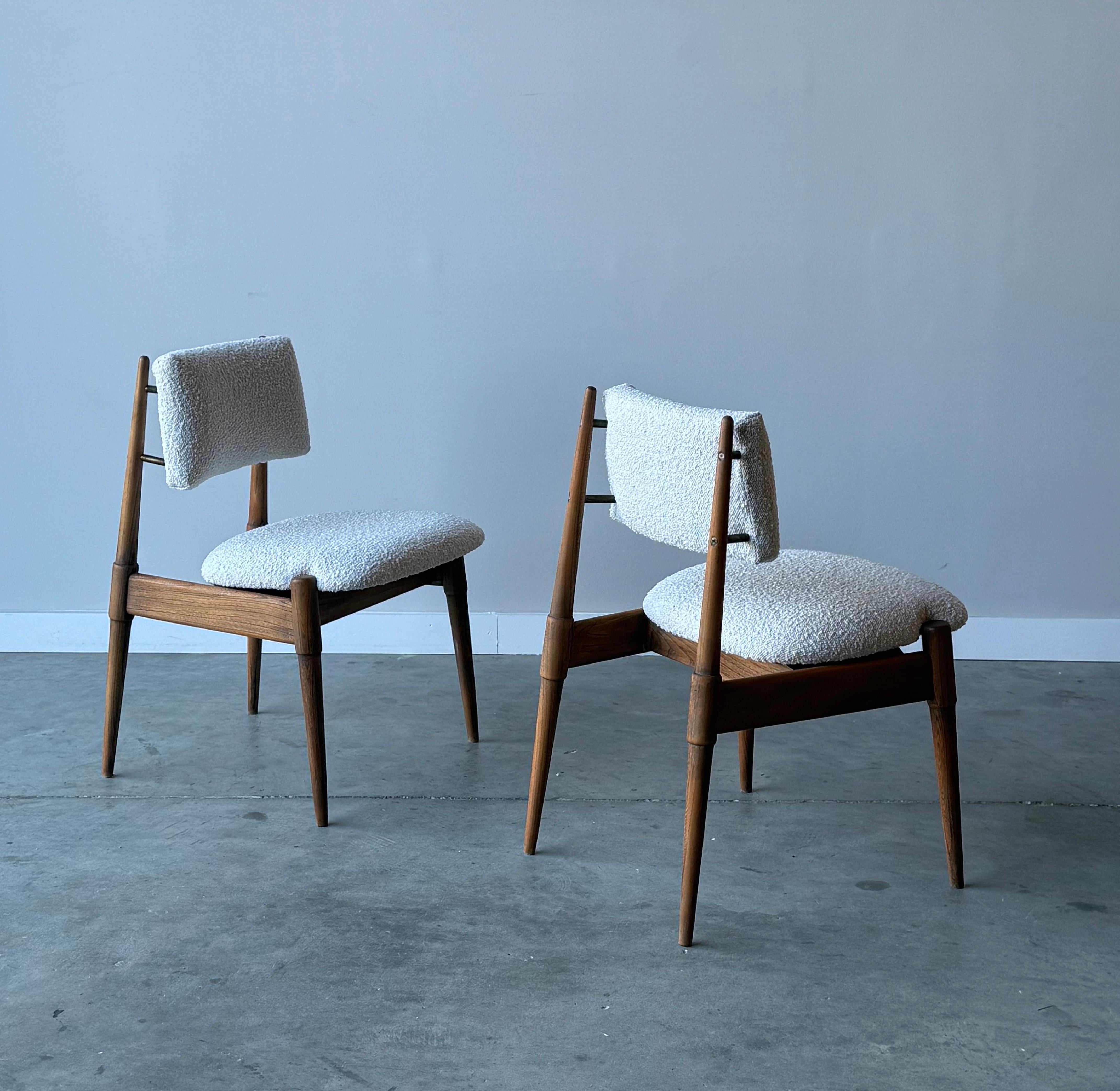 Paire de chaises de l'ère atomique. Les cadres sont en bois, avec des extrémités effilées et une excellente menuiserie. Le ton du bois est riche et le grain du bois est magnifique. Nous avons retapissé cette paire dans un tissu bouclé blanc