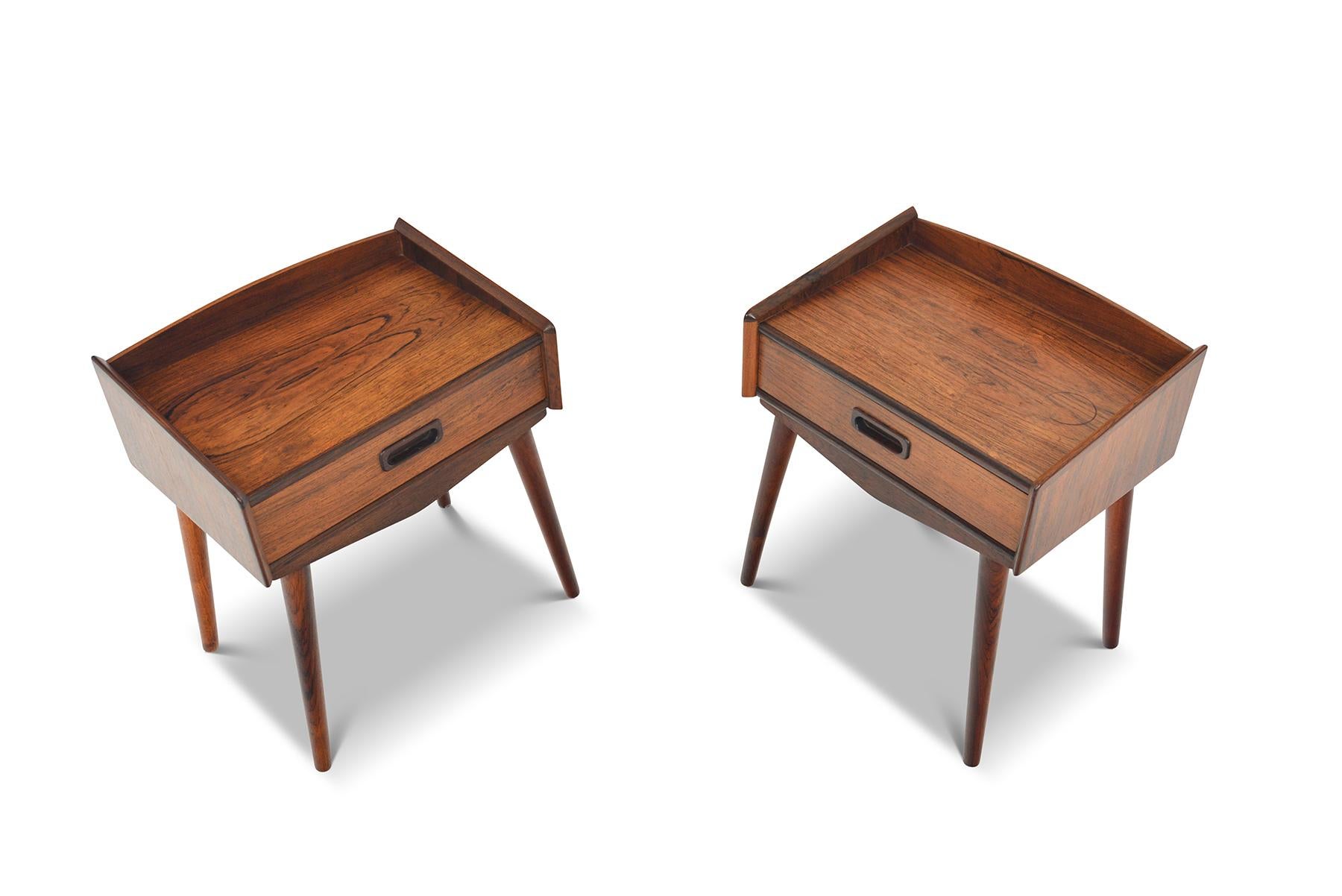 This sweet pair of Danish modern midcentury rosewood nightstands blend form and function seamlessly. A single pullout drawer provides storage for smaller items. Case stands four rosewood spindle legs. In excellent original condition with typical