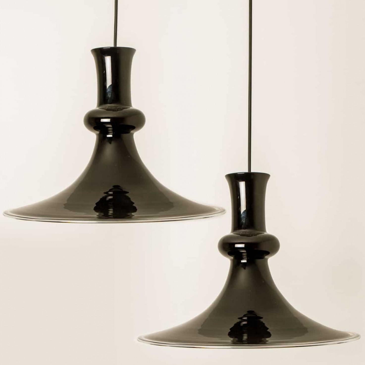 Cette paire de belles lampes en verre de la marque danoise Holmegaard présente une belle couleur aubergine. Le design est signé Michael Bang, un designer dont les œuvres sont aujourd'hui très recherchées par les collectionneurs de la marque. Model