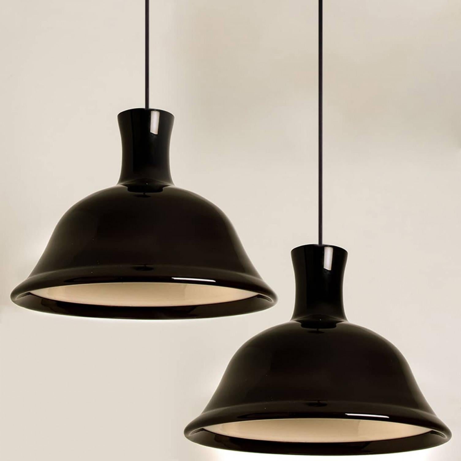 This pair of beautiful glass lamps from the Danish brand Holmegaard has a beautiful aubergine color. The design is by Michael Bang, a designer whose work is highly sought after by collectors of the brand today. Exceptional forms, and statement
